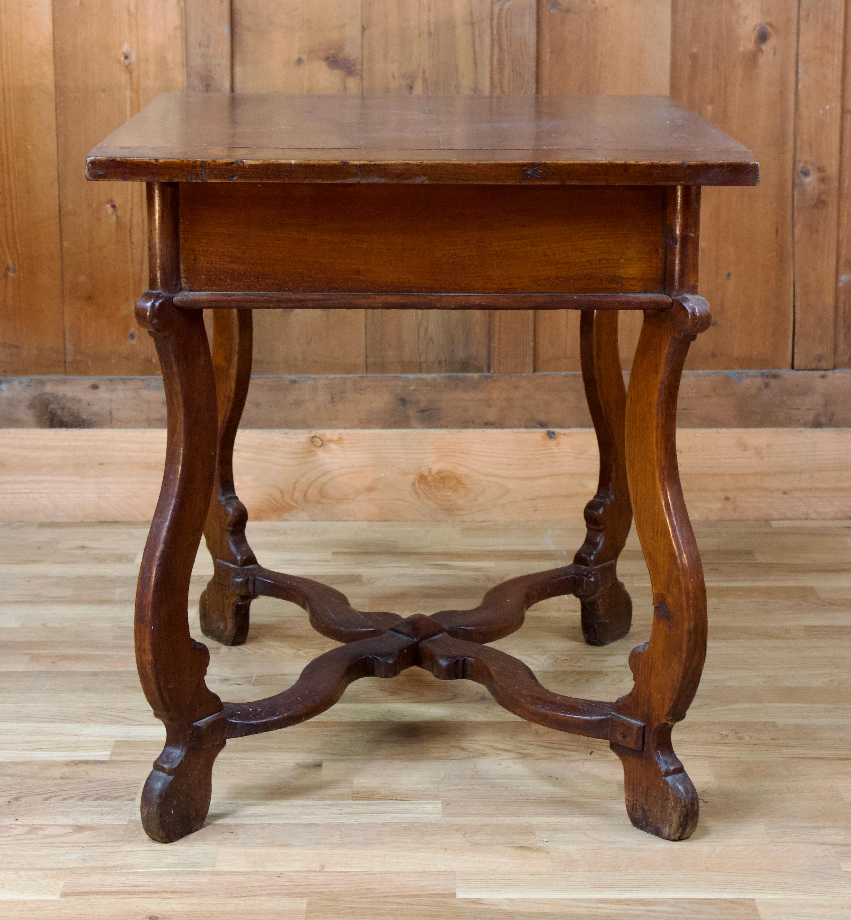 Beautiful cherry wood table from the 19th century, in the style of the 17th, featuring a frieze drawer and four curved legs connected by a spacer.
The lyre-shaped uprights, with elegant curves, are joined by the brace crosspieces of the X-shaped