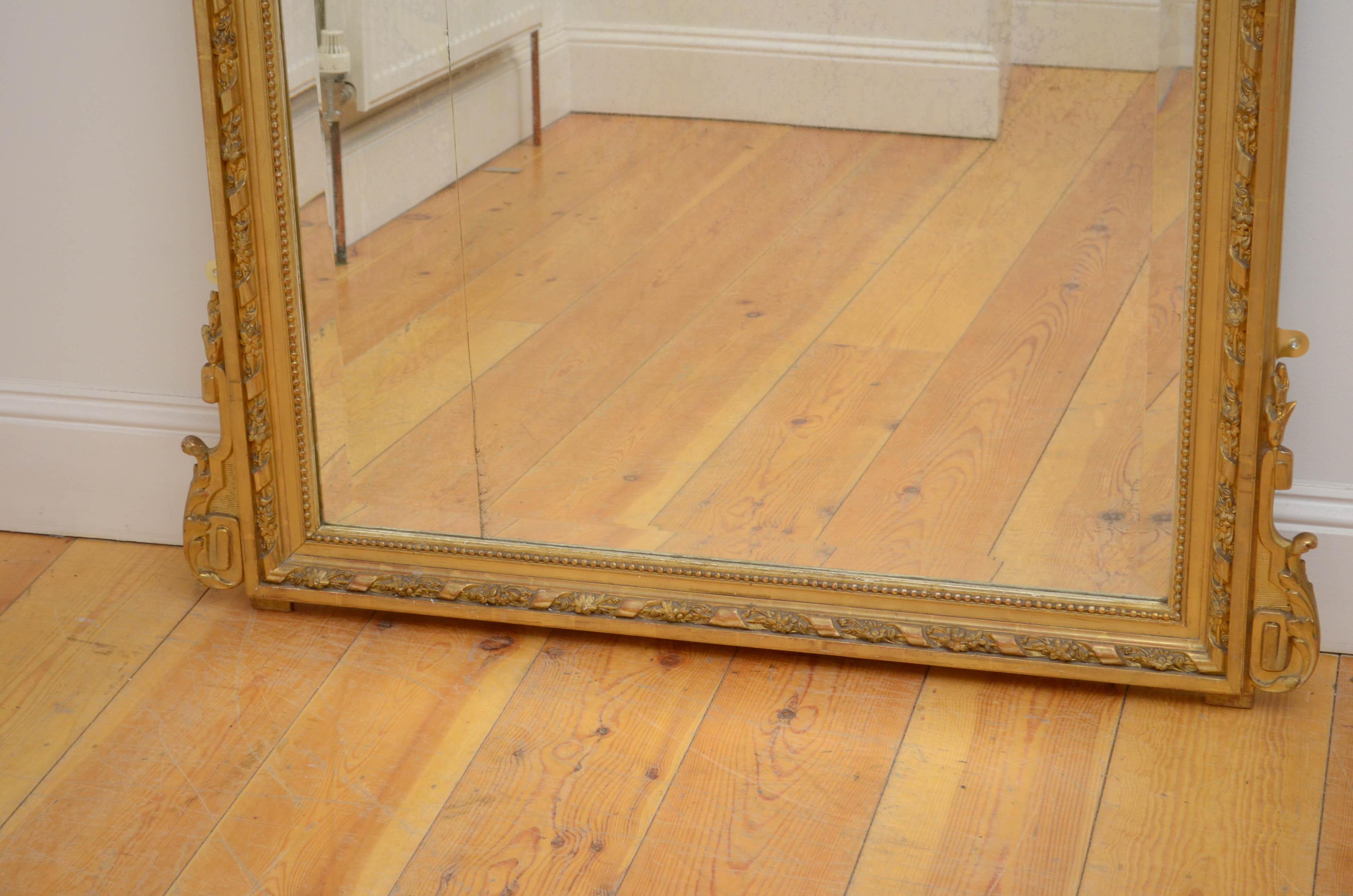 Sn5174 Superb 19th century French gilded wall mirror, having original bevelled edge glass with some imperfection in beautifully carved frame with scrolls to the base and foliage centre crest flanked by floral scrolls and swags. This antique mirror