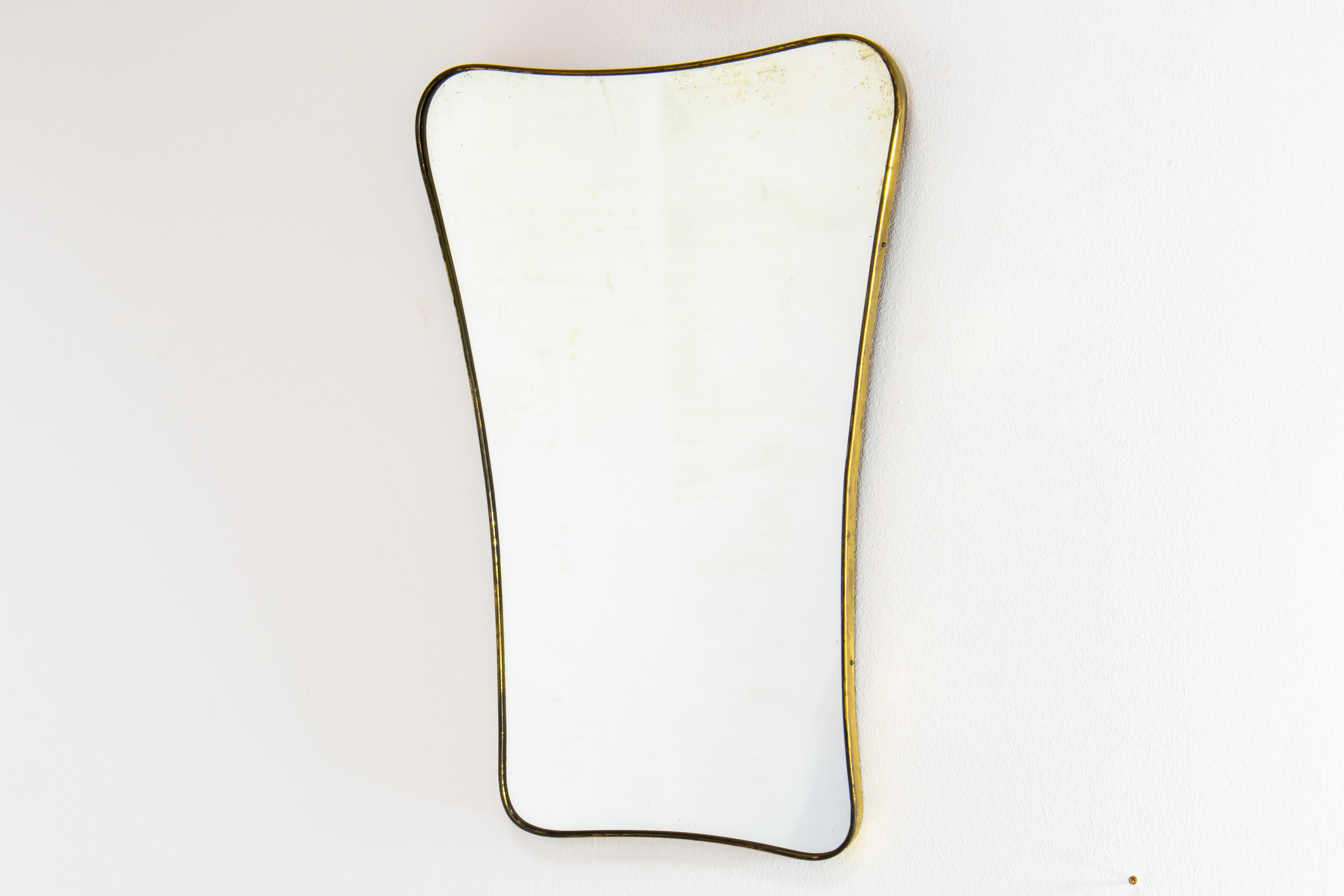 Gio Ponti era Mid-Century Modern wall mirror in patinated brass and original mildly patinated glass. Made in Italy in 1950s.

The shape of the mirror is a very elegant ovaloid with rounded corners and beautiful taper. There is concavity on the top