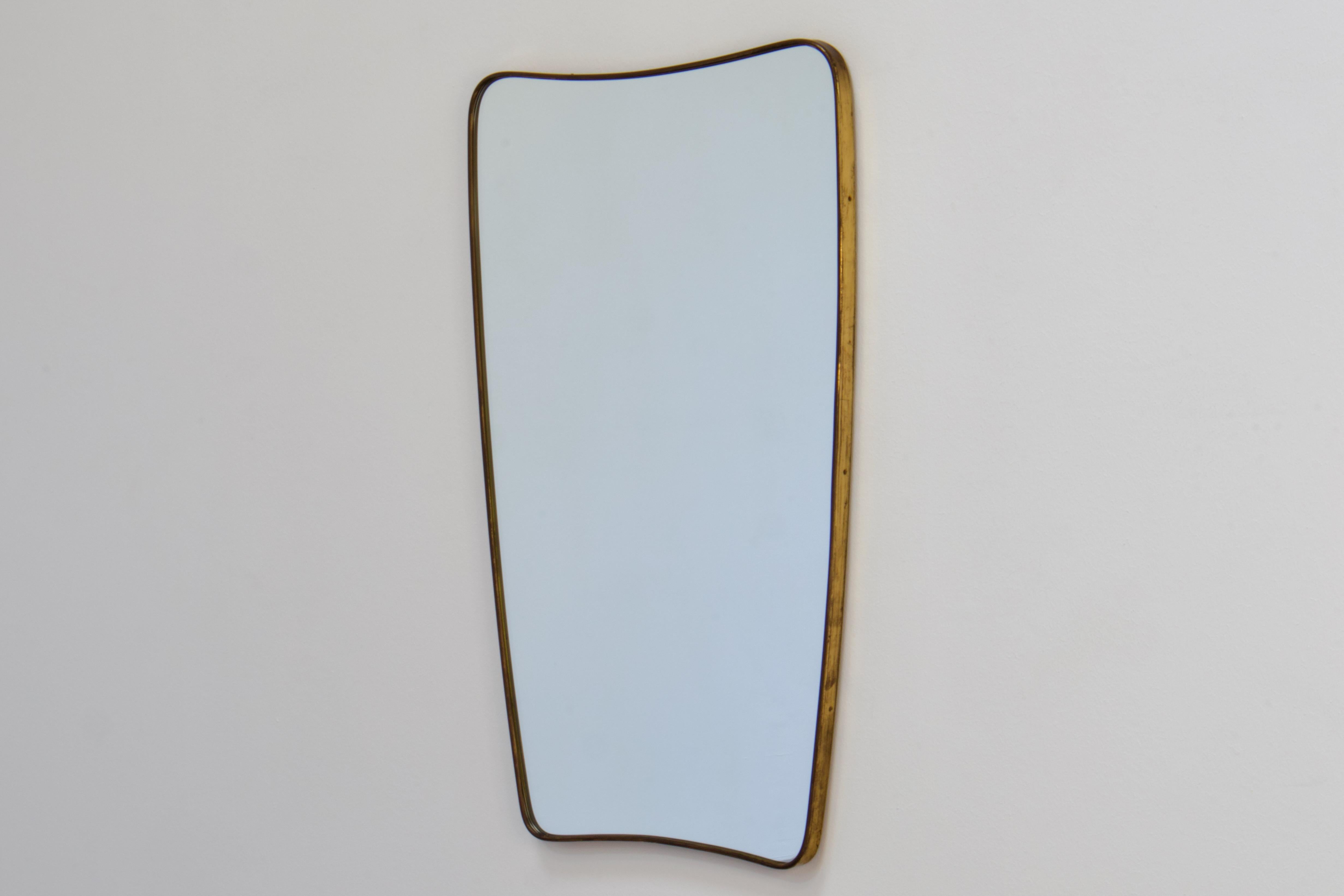 Gio Ponti era Mid-Century Modern wall mirror in patinated brass. Made in Italy in 1950s.

The shape of the mirror is a very elegant ovaloid with rounded corners and beautiful taper. The top is wider, and tapers down to the bottom.

This mirror is