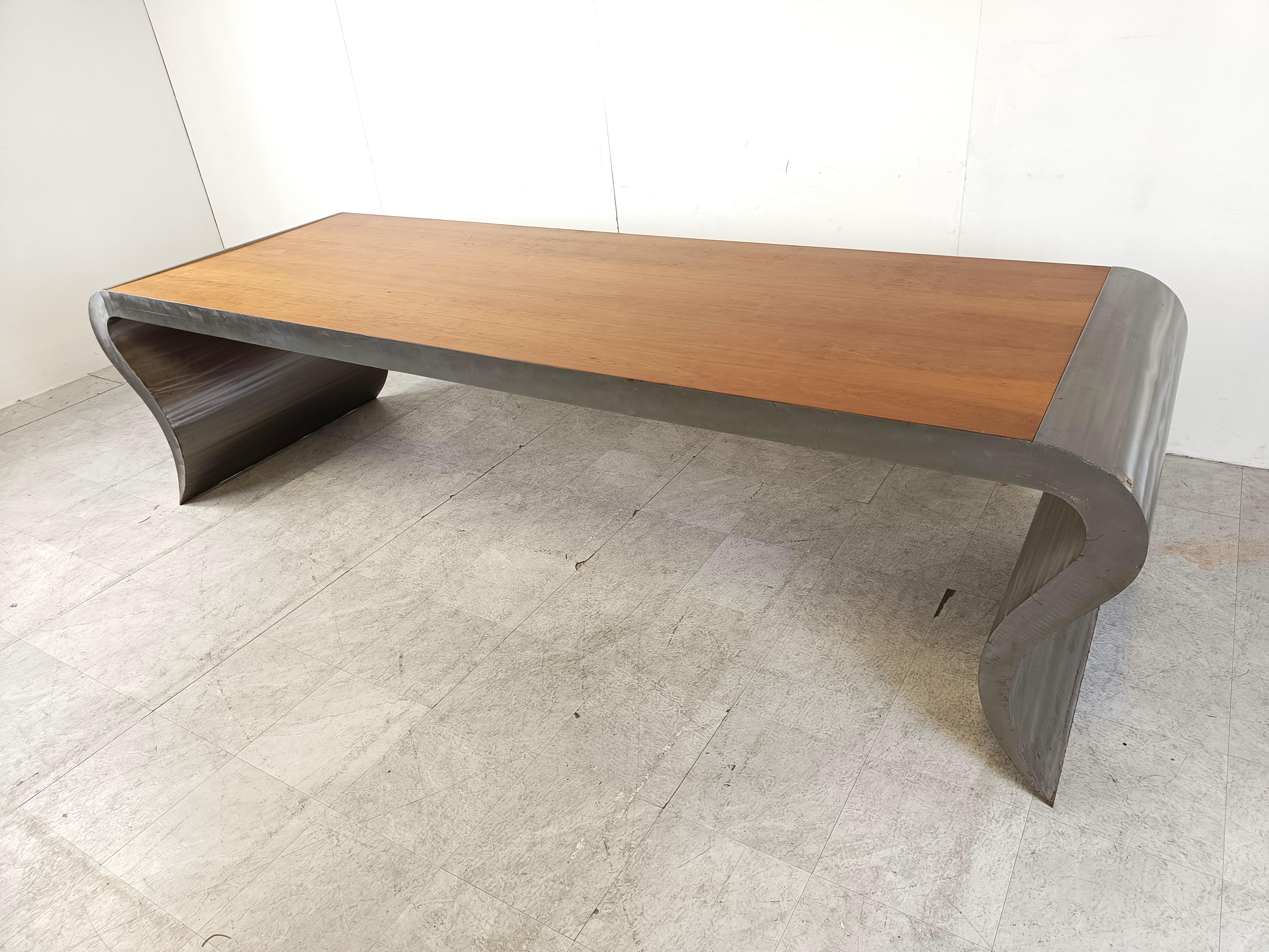 Striking and very large dining table or desk made from a solid wooden top and a brushed aluminum frame with unique curved legs.

Beautiful dining table which really is an eye catcher.

It could also serve as a very unique desk.

1990s -