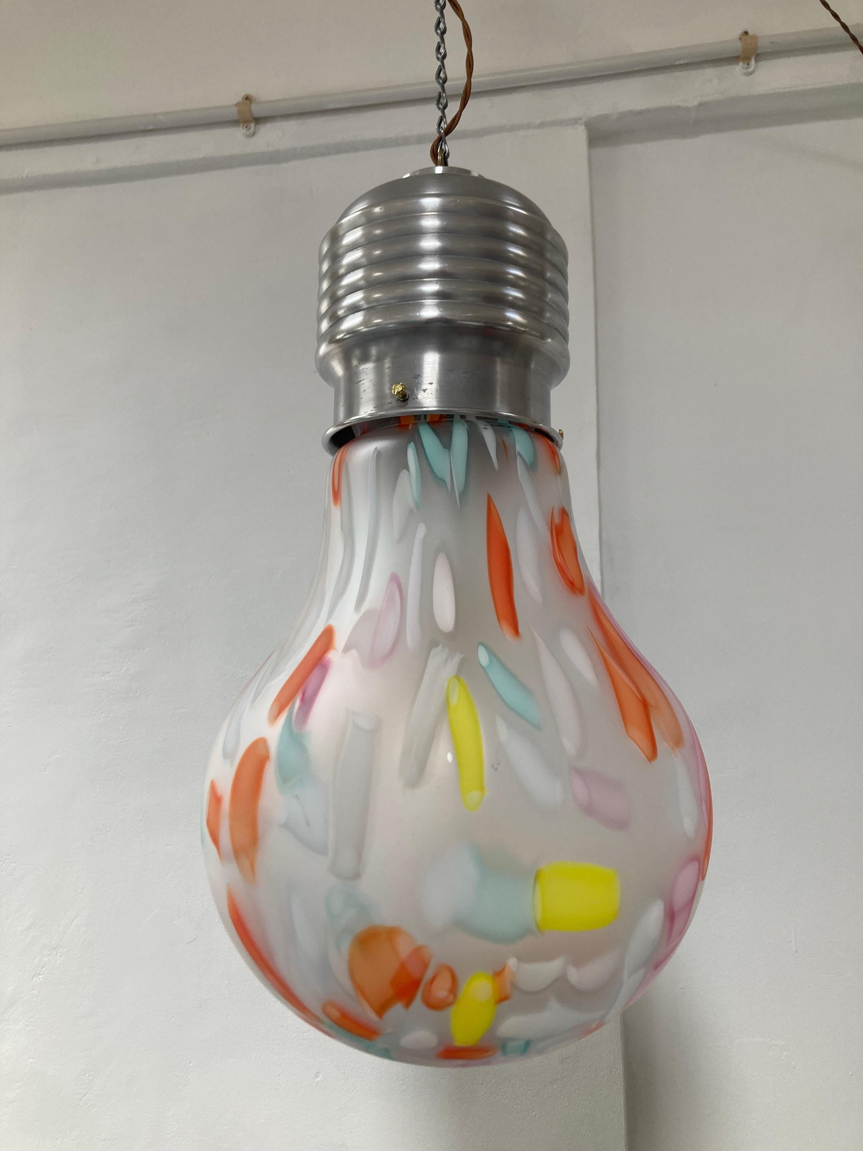 Super size Pop Art 1980's light bulb hanging pendant. This fabulous and fun hanging light resembles a light bulb with a luxe edge. It is mouth blown high quality glass with colours running through the frosted glass, giving a fun glow. The brushed