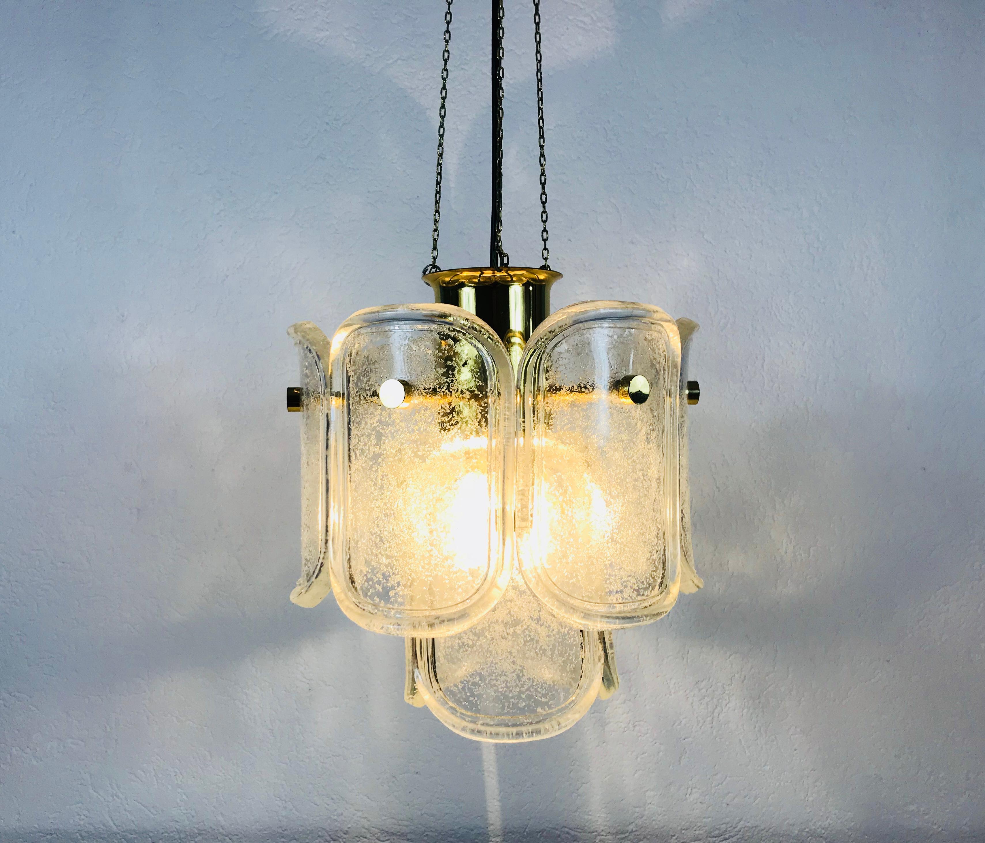 A Limburg ice glass chandelier made in Germany in the 1960s. It is fascinating with its extraordinary glass shapes. Round two-tier brass body with golden chains.

The light requires one E27 light bulb.