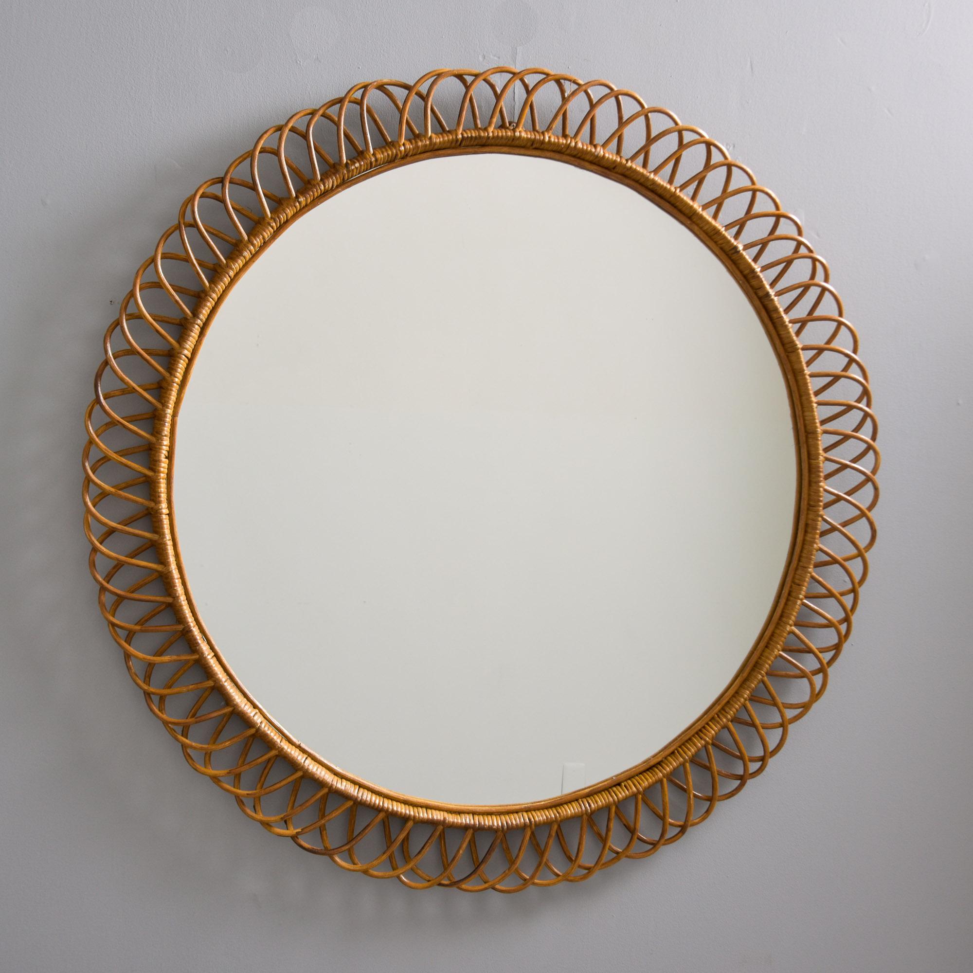 Found in Italy, this round wicker / rattan framed round mirror dates from the late 1960s / early 1970s. The frame of this mirror features an intricate, open-weave border. Wooden back. Very good vintage condition with no breaks to the wicker frame. 