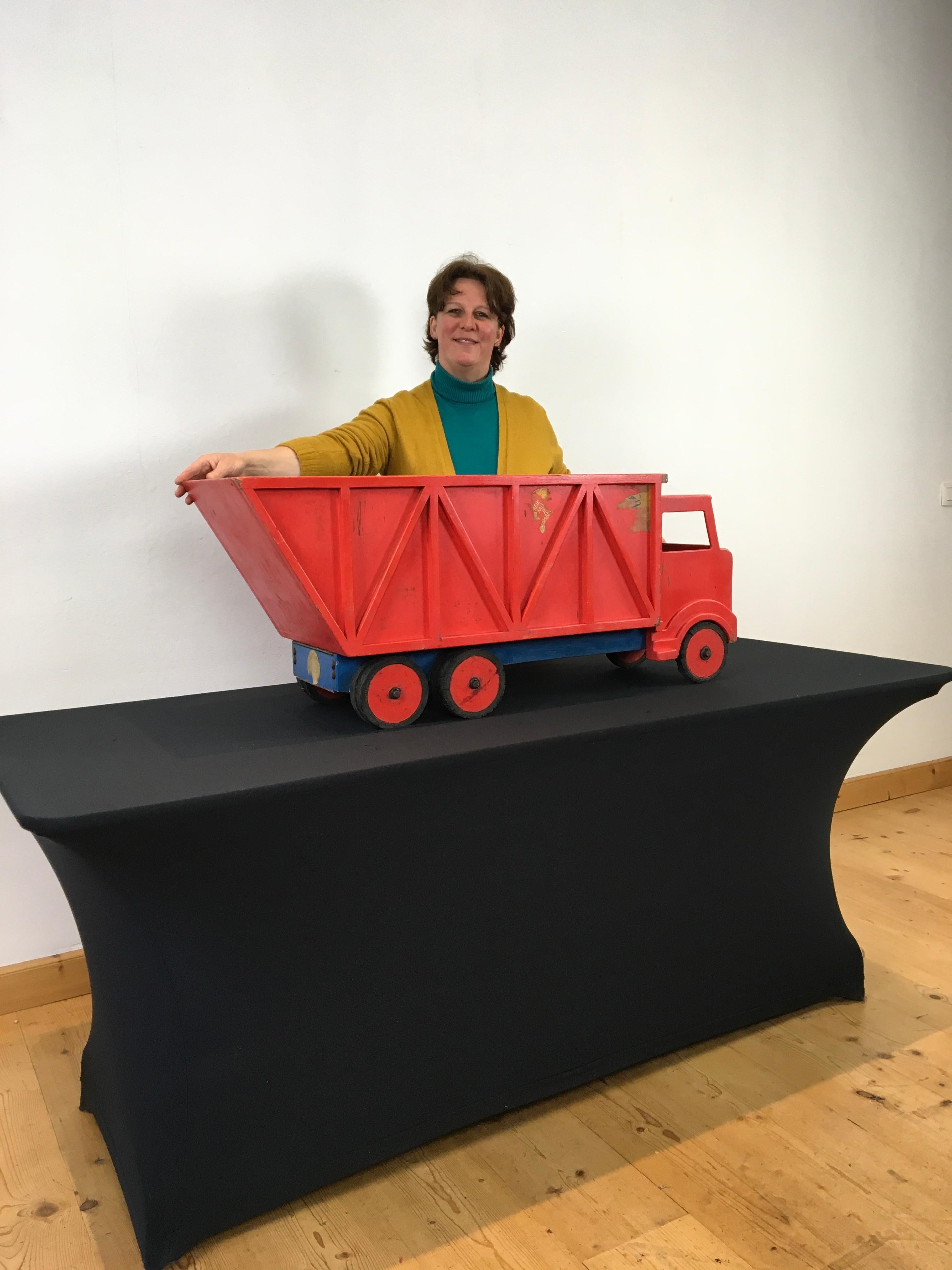 XL red wooden dump truck toy. 
A large toy truck made of red and blue hand-painted wood. 
