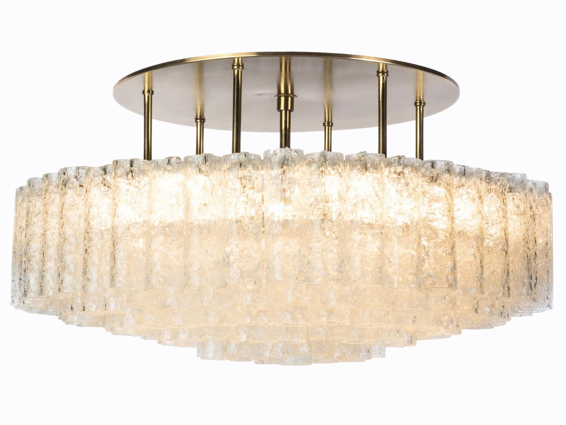 (XL-size) Gorgeous, 1950s Mid-Century Modernist flush mount chandeliers was designed by Doria Leuchten, Germany. It features multi-tiered layers of textured ice glass tubes connected to a circular brushed brass frame. The flush mount with almost 200
