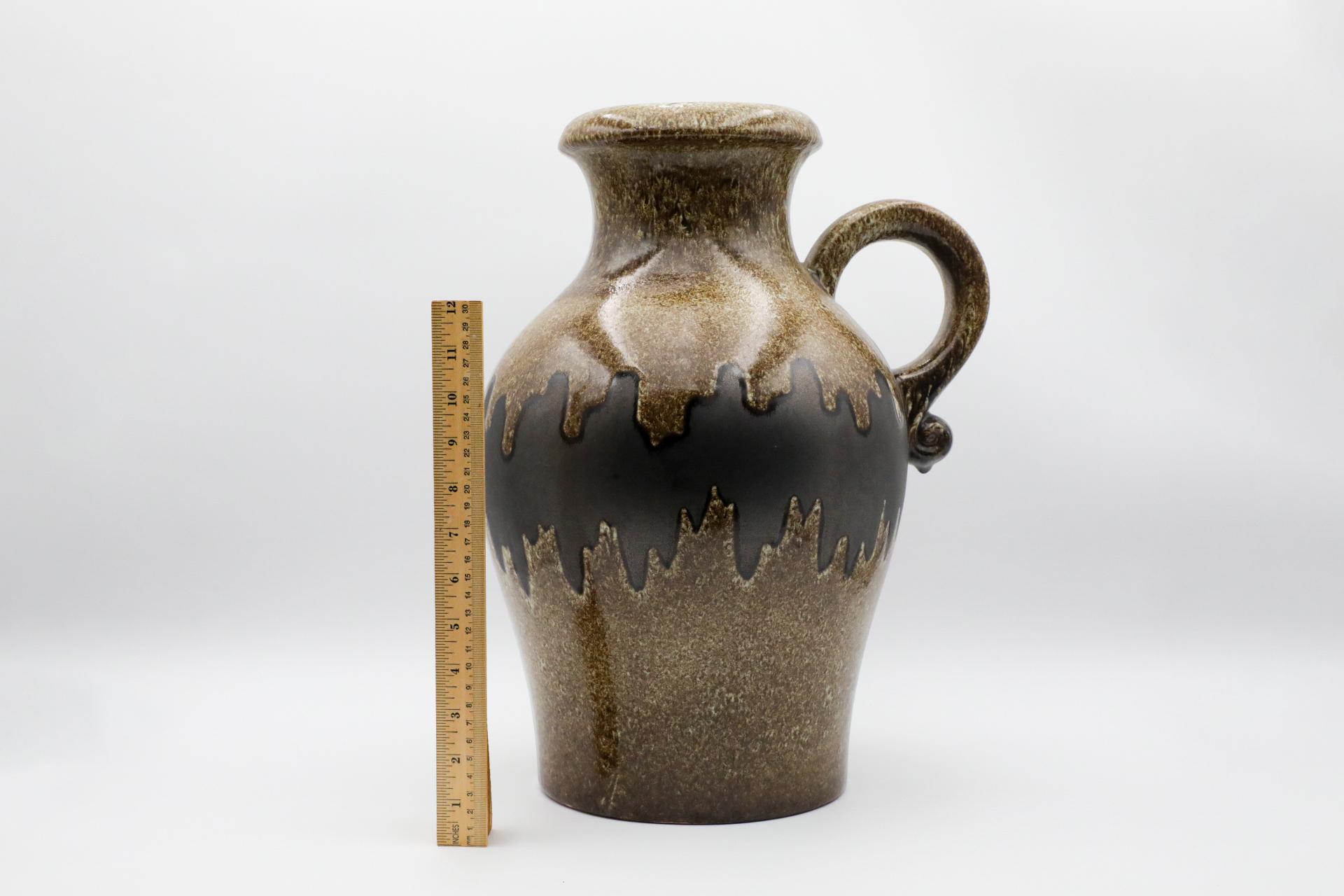 Extra large West German ceramic water jug with handle. Textured brown glaze with wavy dark brown belt. In original condition with wear consistent with age and use. Marked 490-42 on bottom.