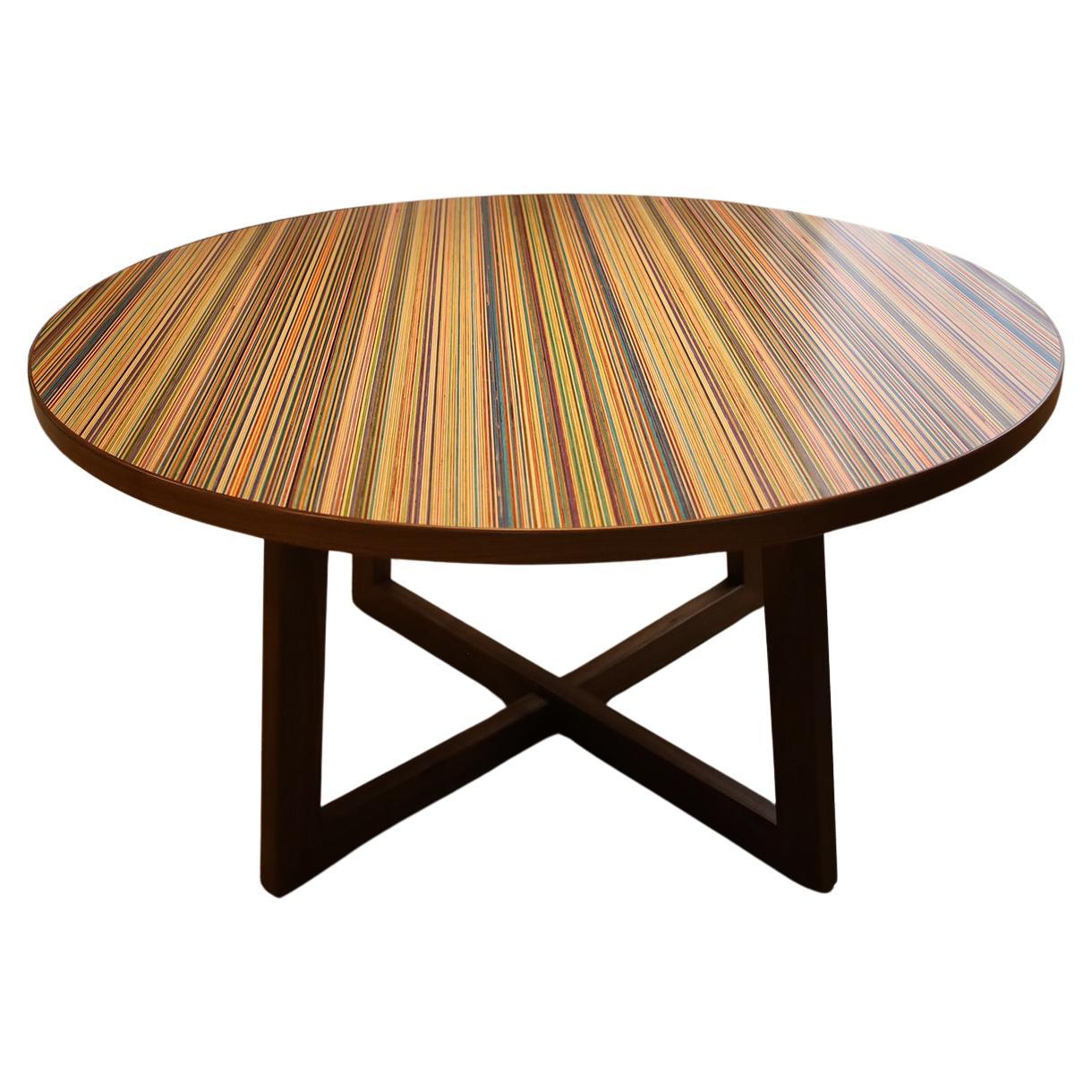 This distinctive round dining table showcases a vibrant skateboard-patterned top that adds a playful touch to any dining space, complemented by solid walnut trim and legs that provide both stability and warmth, making it a stylish and functional
