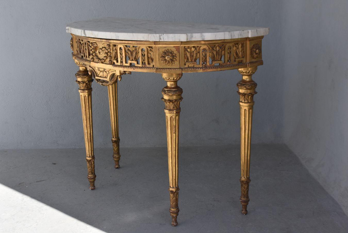 Louis XVI period console. Half moon, wooden carved and gilded white marble top. Riches openwork sculptures on the headband.