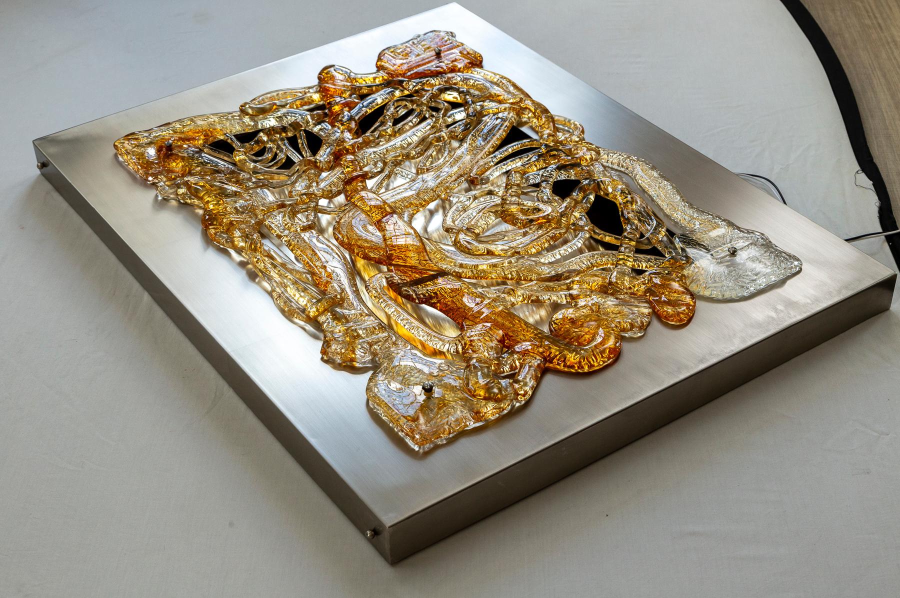 Modern and sculptural large blown icy clear & amber colored glass panel attached to a rectangular shaped matte nickel on brass frame.

Originally the chrome back was electrified with surrounding sockets which has been replaced with LED dimmable