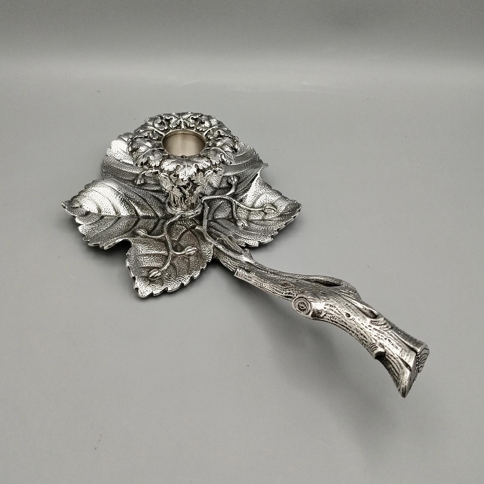 Candlestick in solid silver made with the casting technique and subsequently engraved and chiseled.
The object reproduces 5 rose leaves with a branch-shaped handle.
The candle holder, in the center of the composition of leaves, has a crown of
