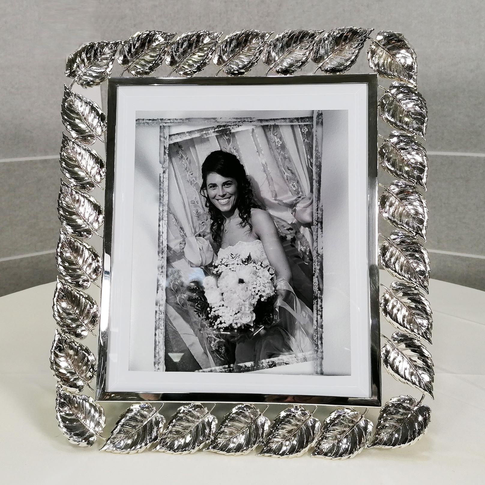 Solid silver photo frame.
The frame is made of a shiny rectangular silver plate where chiseled silver plate leaves have been welded onto the entire surface. The back was done in blue velvet.
The rectangular glass has been embellished with