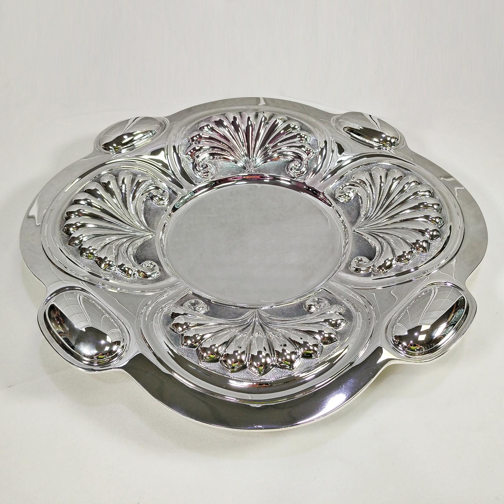 Gran centro de mesa de plata de ley.
El centro de mesa se hizo completamente a mano, moldeado, repujado y cincelado.
La forma es un cuadrado redondeado con grandes óvalos en los cuatro lados que quedan brillantes.
Cuatro grandes conchas se repujaron