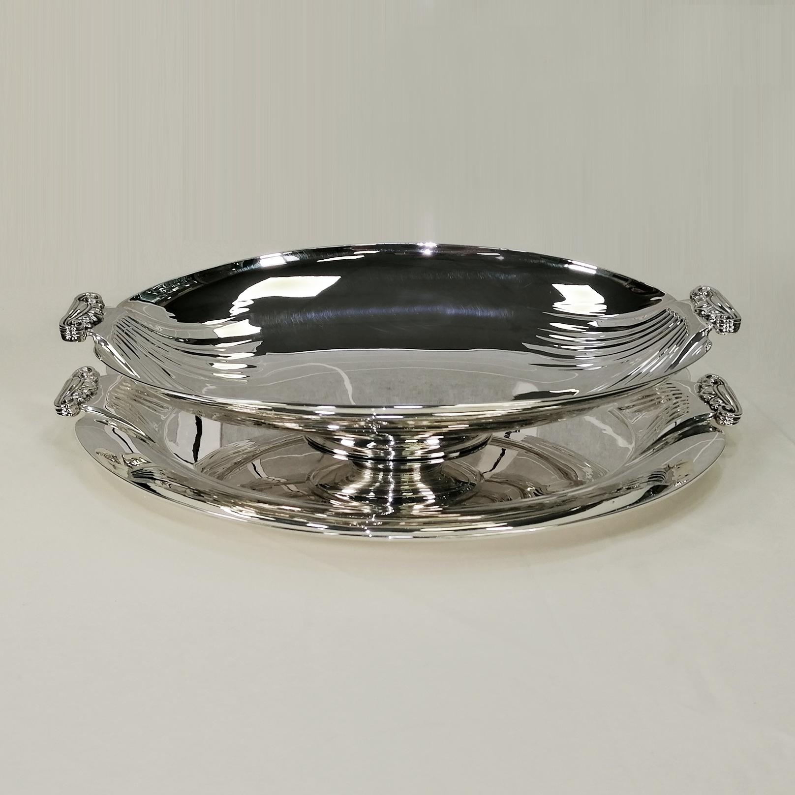 Large impressive sterling silver centerpiece comprising Jatte and tray.
The tray, with a large support surface, is oval with a raised and edged edge.
Striations have been embossed on both sides, ending with 2 capital-shaped handles made with the