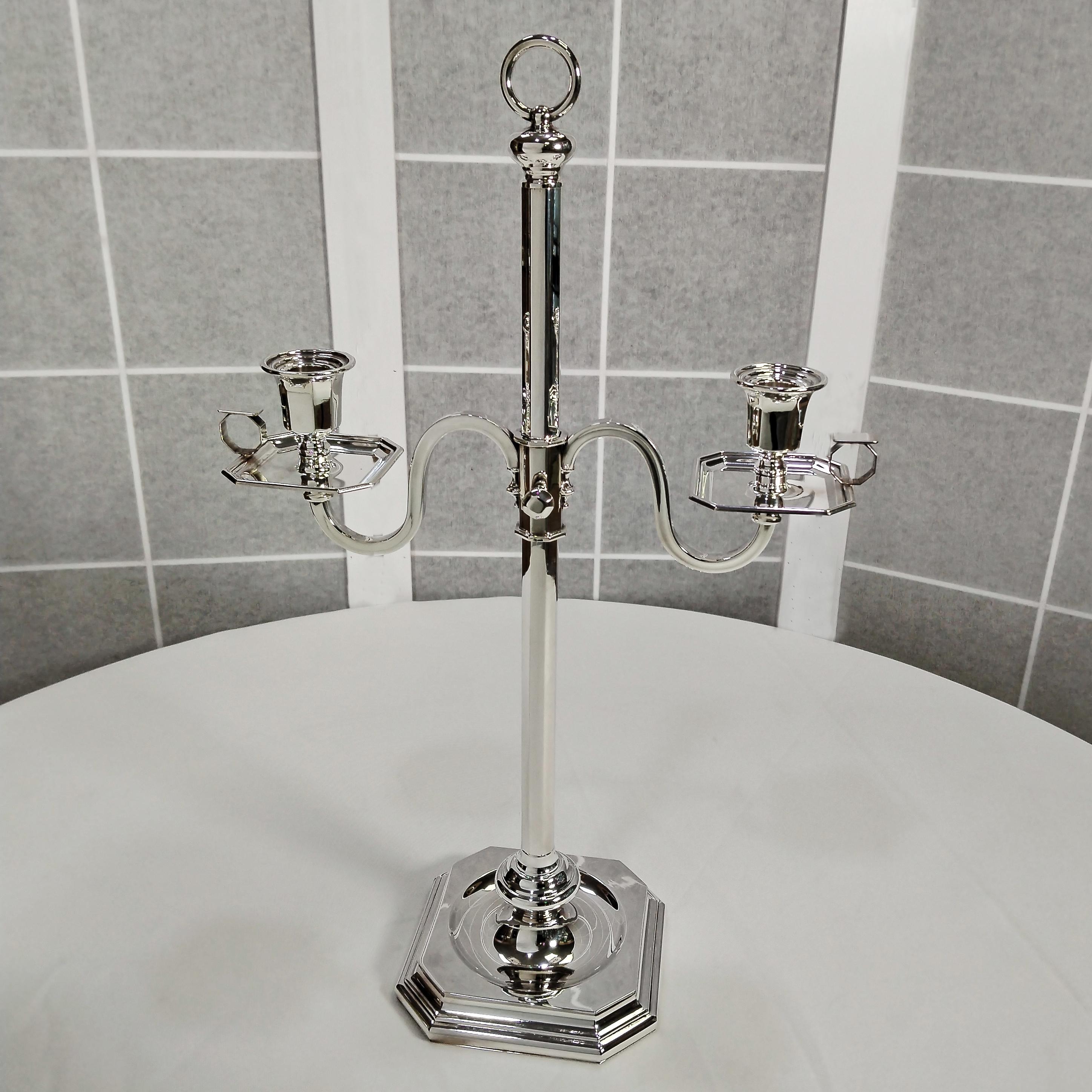 Candelabro octogonal telescópico con 2 llamas.
El candelabro tiene una base cuadrada/octogonal escalonada.
En el centro de la base se ha practicado un rebaje en el que se ha soldado un casquillo redondo del que parte un vástago octogonal.
Sobre este