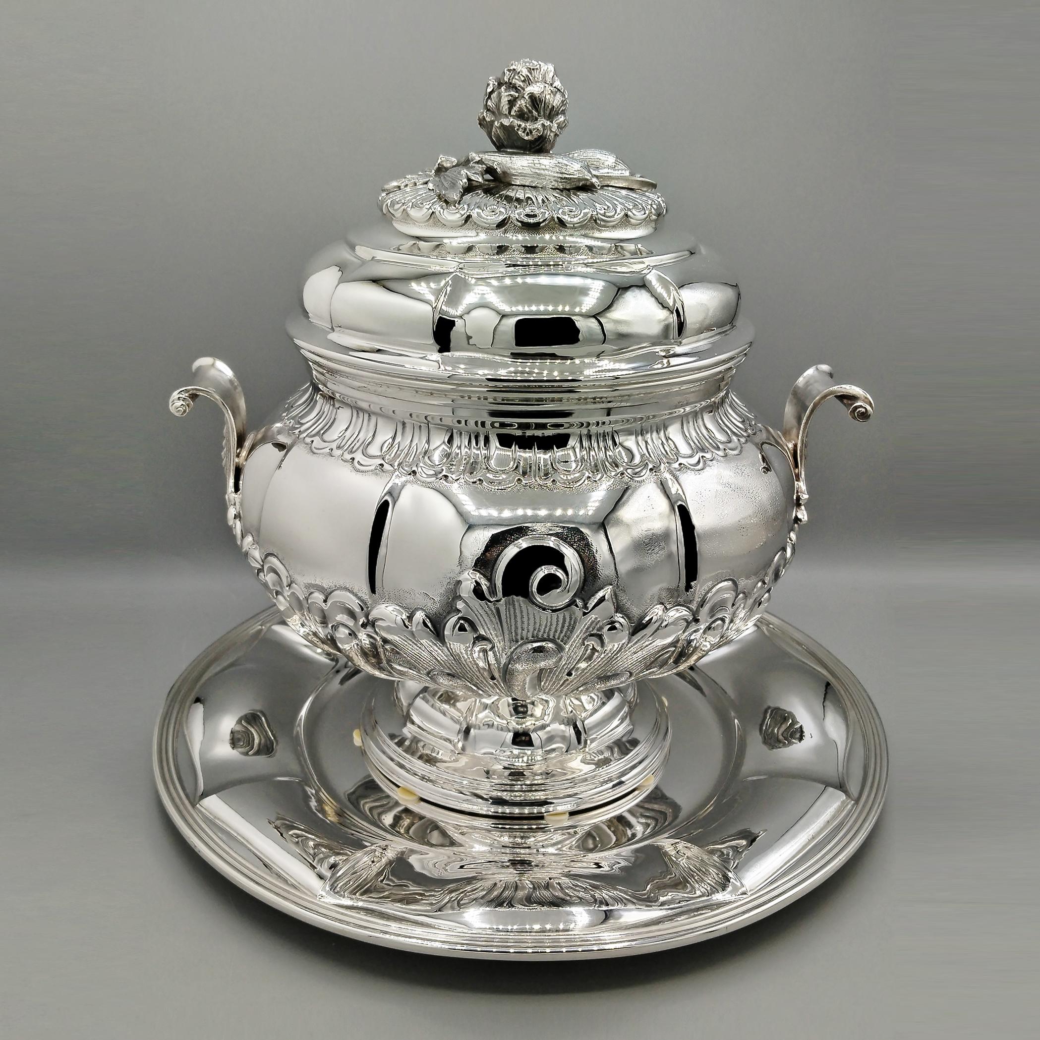 Soupière ronde en argent de style baroque avec plat.
Le plat est rond et présente des rainures en relief qui se poursuivent géométriquement sur le corps et le couvercle de la soupière.
Une base ronde cannelée et étagée est soudée à la partie