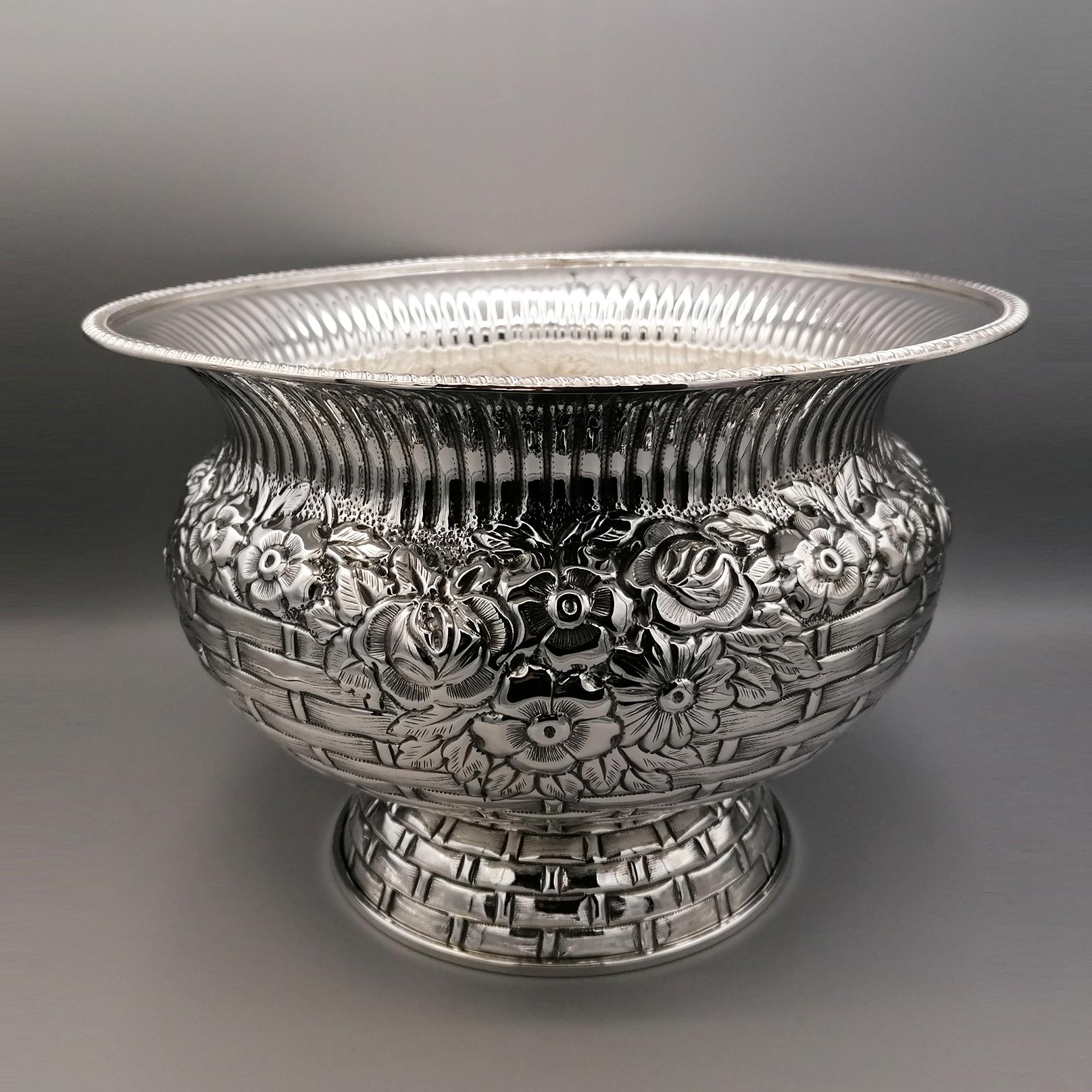 Imposing flower basket in solid 800 silver with base.
The body of the centerpiece is rounded and completely embossed by hand with a wicker basket design.
In the upper part of the central part, flowers of different types with their leaves have been