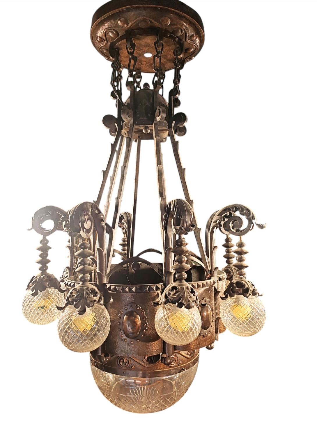 

Questo lampadario austro-ungarico, realizzato nel 1900, è un esempio eccezionale del movimento Arts and Crafts, uno stile rinomato per la sua enfasi sull'artigianato, i materiali naturali e i dettagli intricati. Realizzato in bronzo forgiato a