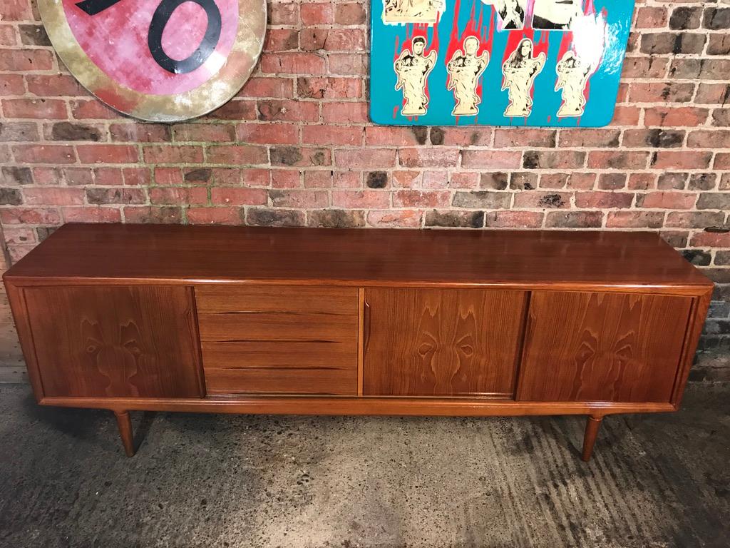 Stunning midcentury designed by Gunni Omann teak sideboard by ACO Møbler, 1960s, lovely top and sliding doors, fully lined (four) drawers and stands on nice solid teak legs (this is the very scarce model that has the round legs without the