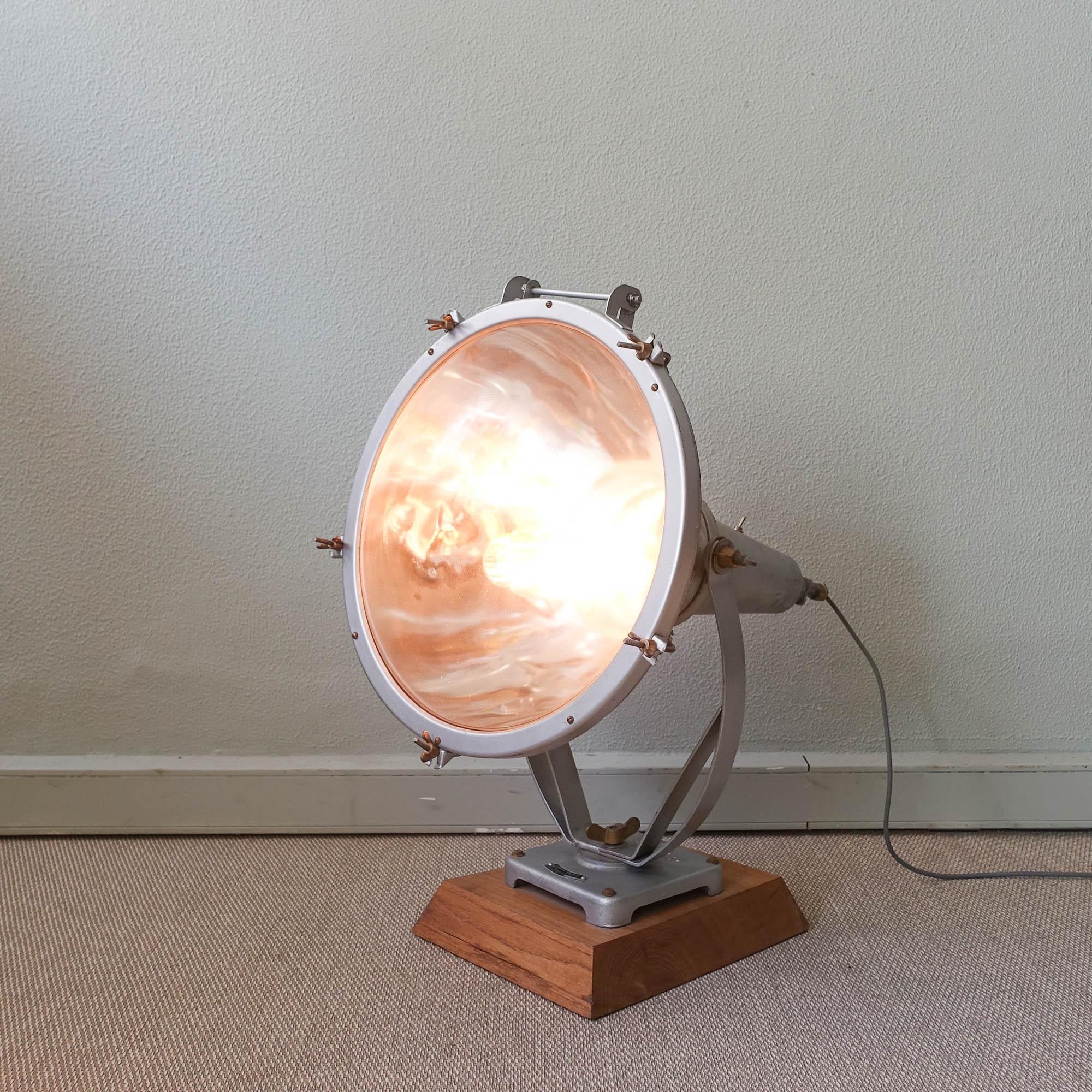 This exterior focus lamp was designed and manufactured by Mazda Paris, in France during the 1930s. It is made of metal with glass diffuser in front and metal mirror inside. It's set on a geometric wooden base. In original and good condition.