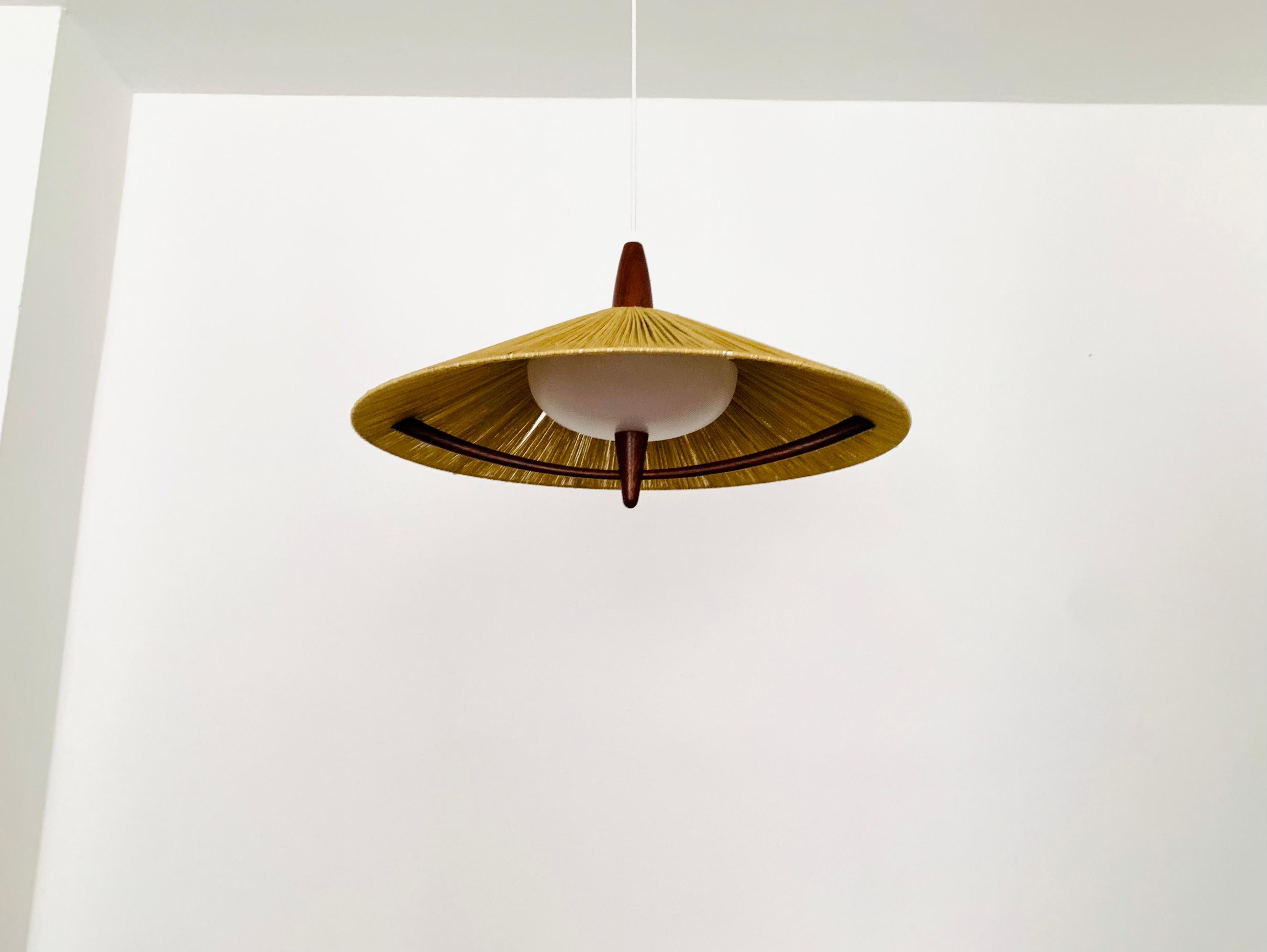 Exceptionally beautiful and very large pendant light from the 1960s.
The design is very unusual.
The shape and the materials create a warm and very pleasant light.
The teak details are beautifully shaped.

Condition:

Good vintage condition