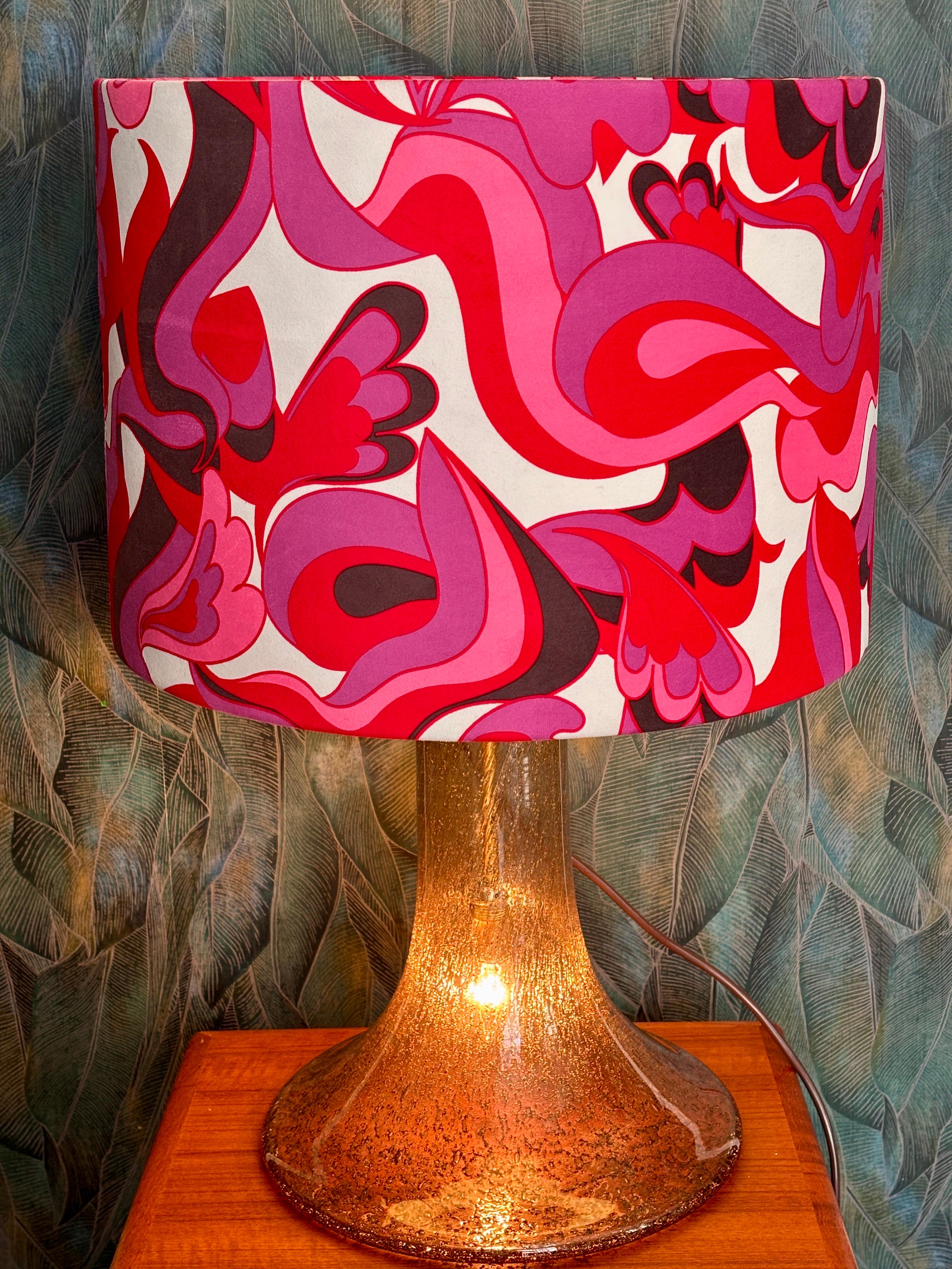 Très grande et magnifique lampe de table en verre soufflé à la main par Peill & Putzler.
La lampe est dotée d'un socle en verre épais et lourd et d'un abat-jour en plastique épais recouvert d'un tissu à motifs. La base et la teinte sont toutes deux