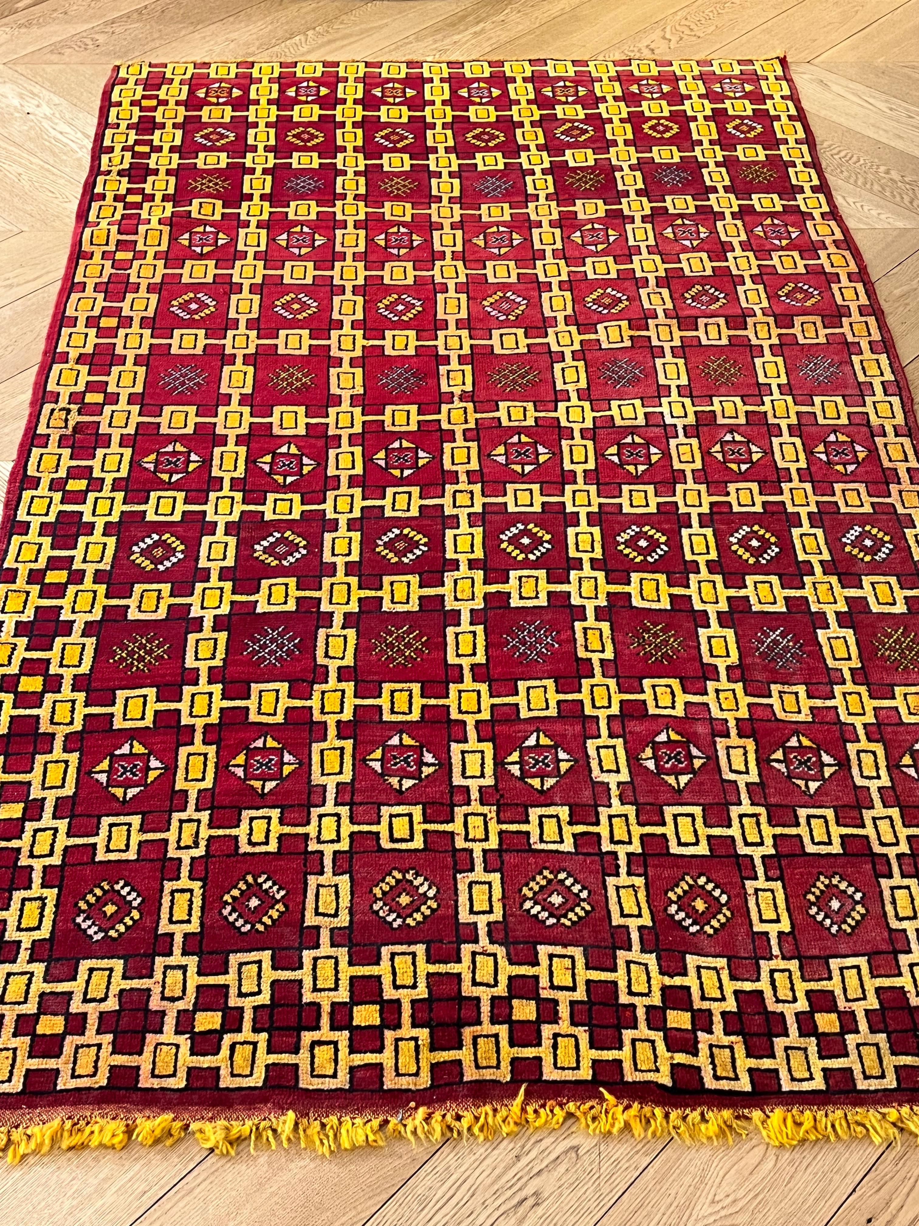 Ce tapis berbère de la région d'Ouarzadeh présente une structure caractéristique en laine de couleur safran. La décoration est faite d'éléments répétitifs à structure géométrique, avec des éléments traditionnels des populations nomades. De nombreux