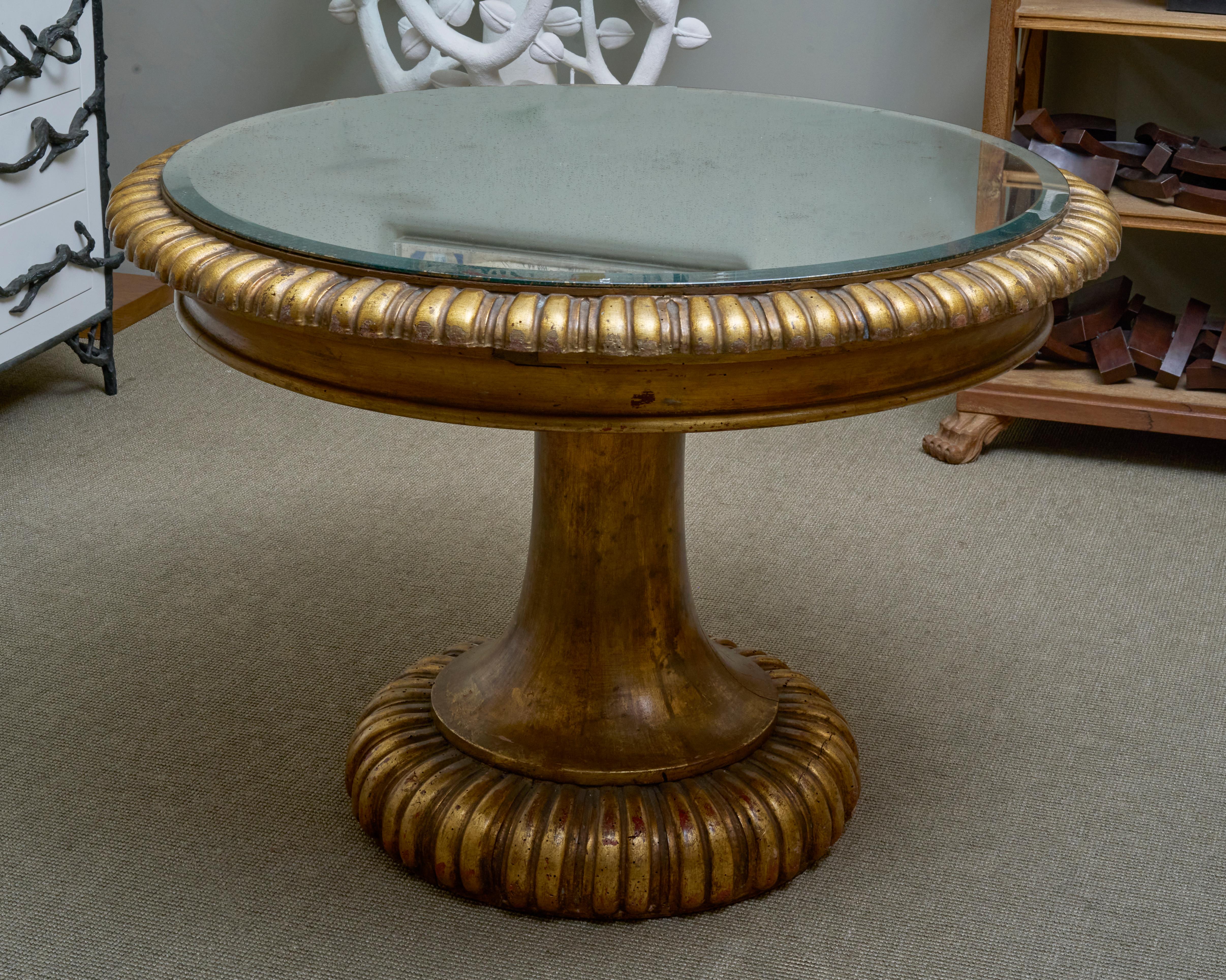Bois peint et doré à décor de godrons, plateau circulaire en verre reposant sur un fût balustre
XXème siècle
H 77 x 106 cm

Unsigned - Table Gueridon 
Painted and gilded wood with gadroon decoration, circular glass top, baluster shaft
XXth Century