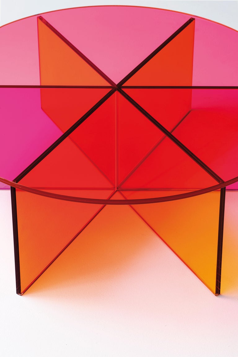 XXX low table is shown here in the transparent pink, orange and yellow coloured glass, and in the small size of the two tables. Low table realized in transparent pink, orange and yellow coloured glass. The base is obtained by gluing six laminated,