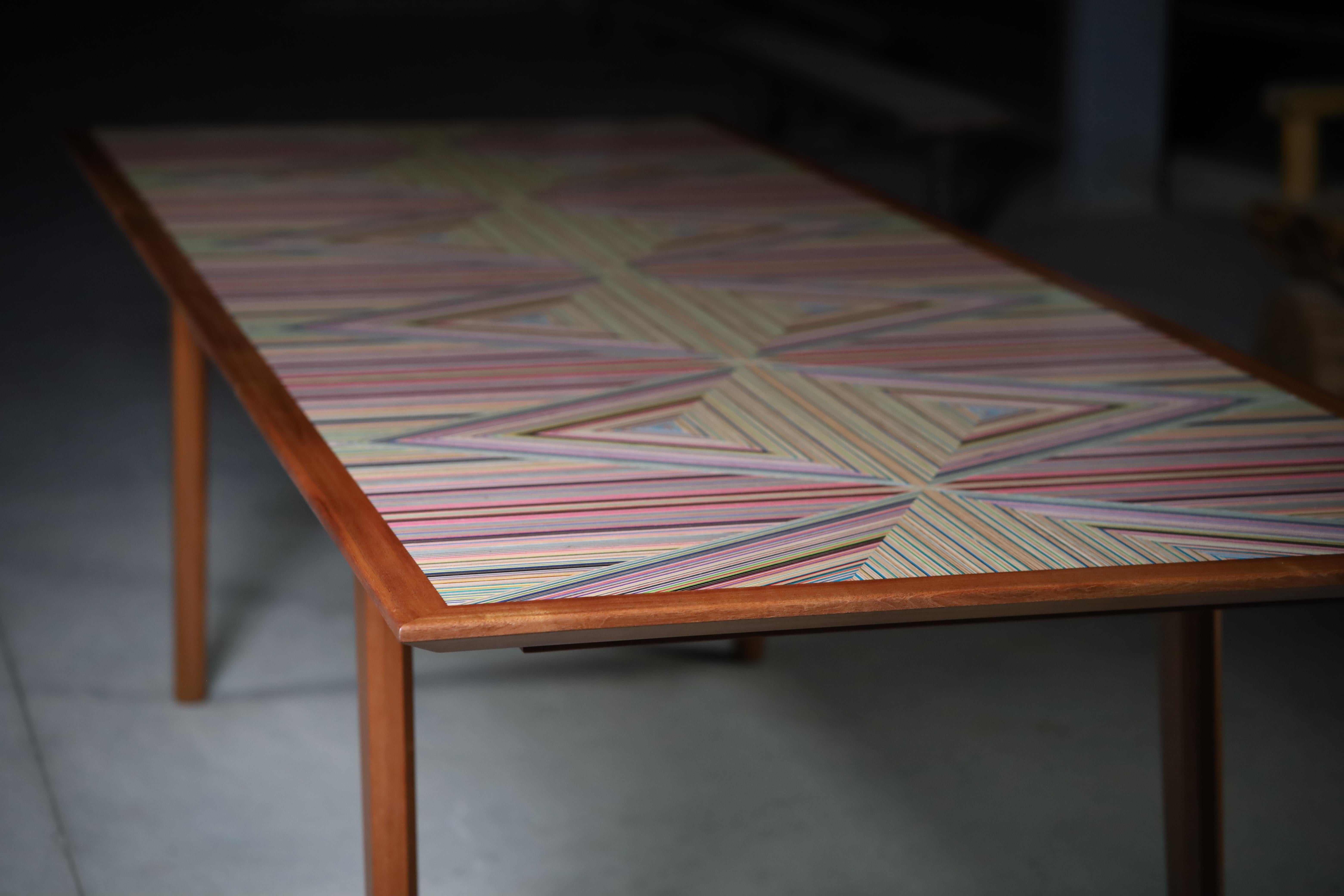 Cette table de salle à manger à feuilles unique est dotée d'un plateau à motif de skateboard en diamant vibrant,
complété par des garnitures en sapelli massif et d'élégants pieds fuselés,

La palette de couleurs des skateboards peut varier. 
La
