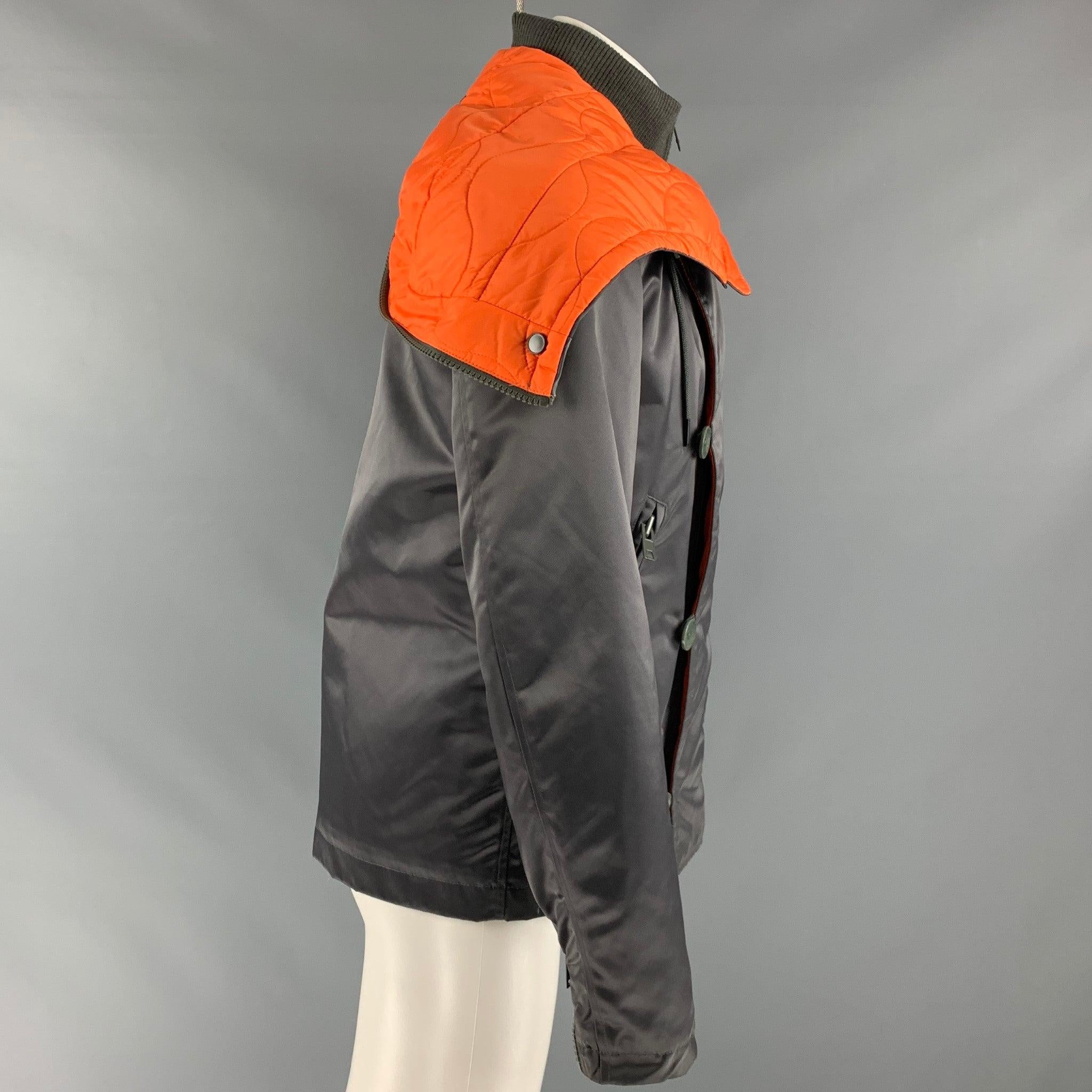 Y-3 x ADIDAS jacket comes in a grey and orange polyamide blend woven material featuring a two-in-one style, an front panel with buttons, drawstring,
 removable hood layer, zipper cuffs, and zip up pockets.Good Pre-Owned Condition. Moderate signs of