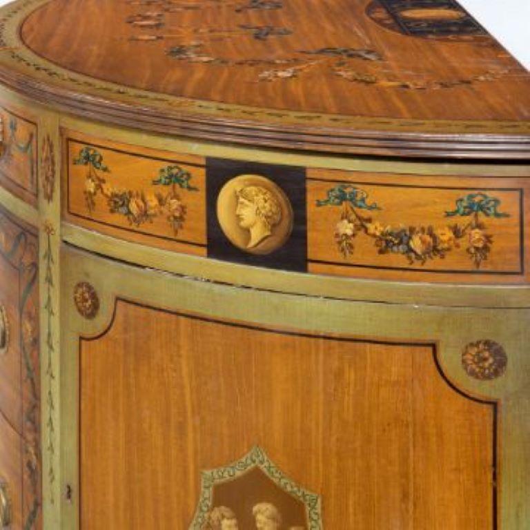 Y A PAIR OF POLYCHROME DECORATED SATINWOOD DEMI-LUNE COMMODES20TH CENTURY, IN THE GEORGE III STYLEEach with flower swagged top above a frieze drawer painted with a classical urn and floral swags, above two further drawers painted with a classical