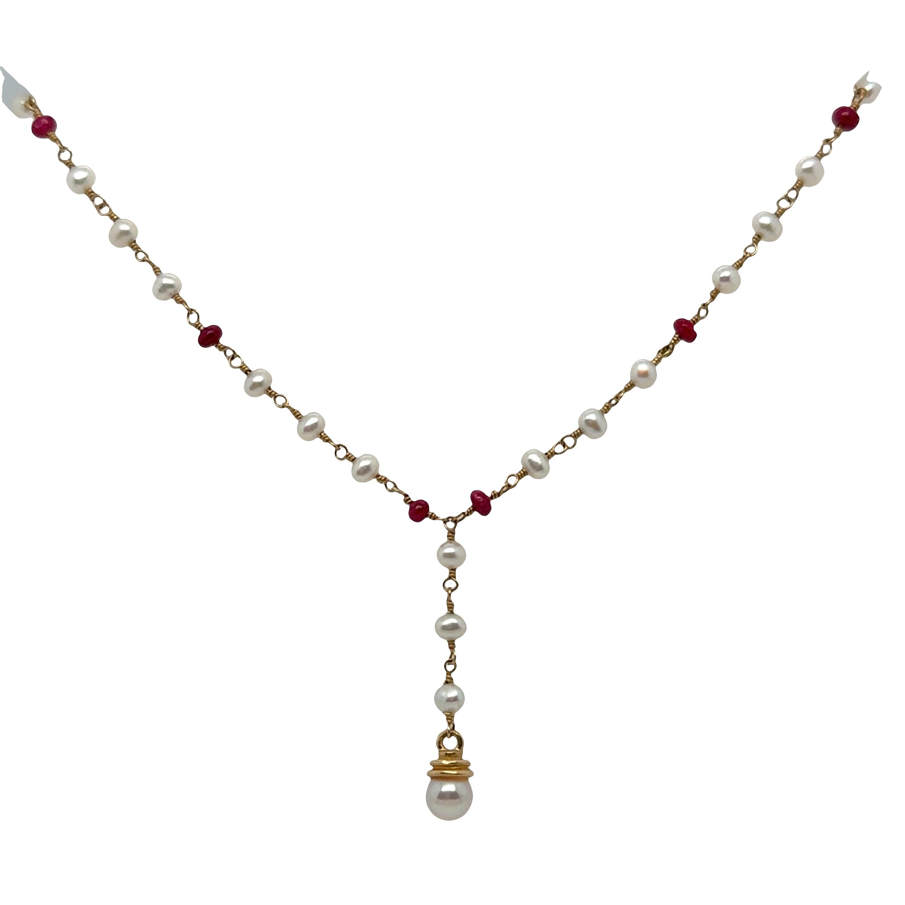 A delicate and feminine Y-shaped necklace crafted with timeless materials and artisanal care. This elegant piece features a graceful strand of natural white pearls and deep red ruby beads, all linked by hand-twisted 14k yellow gold wire for a
