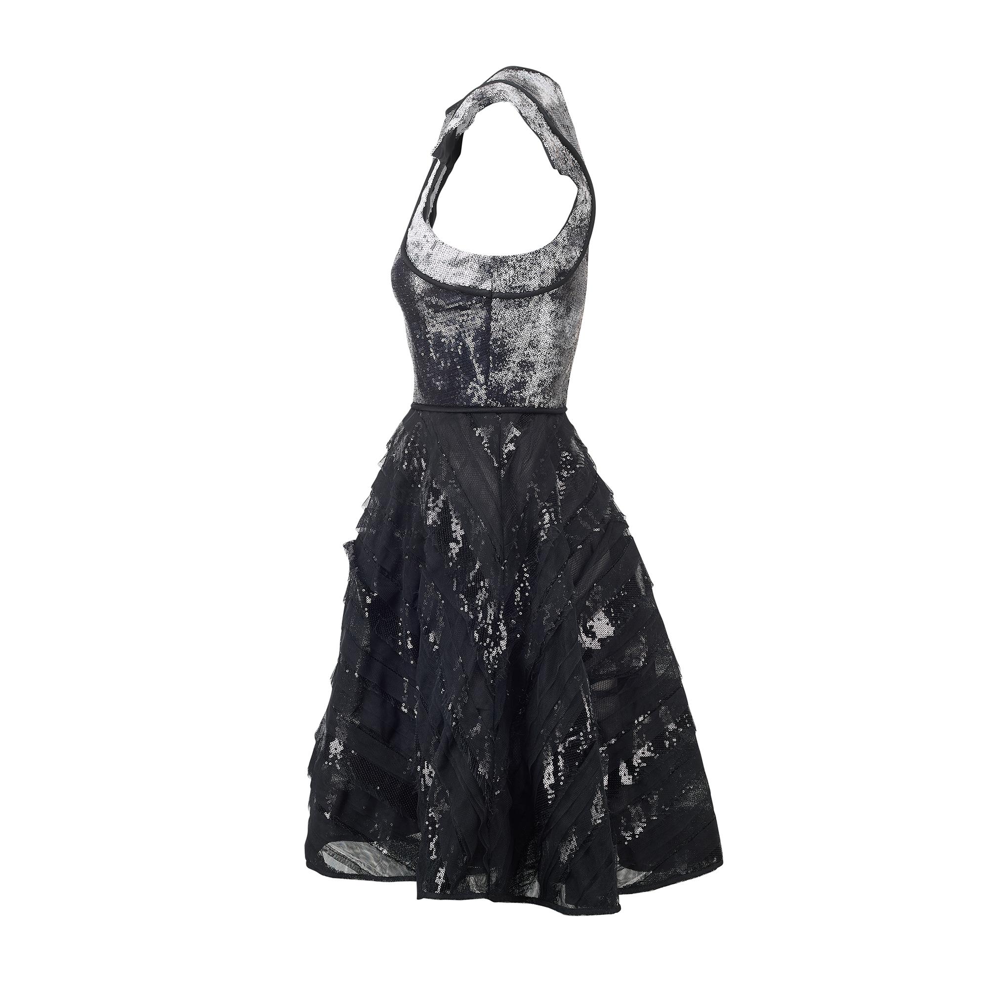 Dieses Partykleid wurde vom Braut- und Abendkleiddesigner David Fielden in den späten 1990er bis frühen 2000er Jahren entworfen. Es ist aus dicker schwarzer Seide geschneidert und mit winzigen ringförmigen Pailletten besetzt. Diese sind in