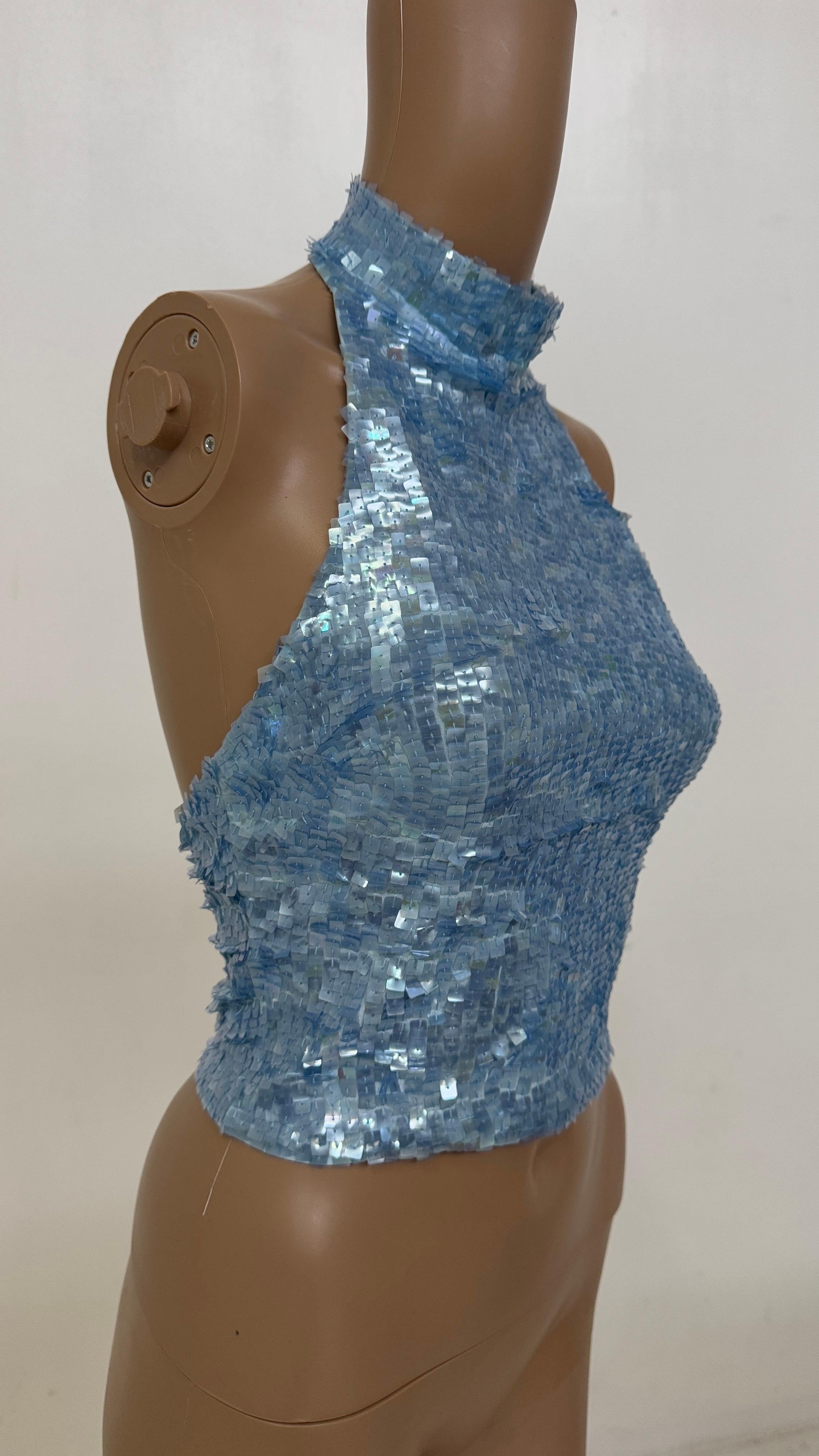 This eye-catching halter top by Jessie Norman is a rare Y2K gem made in a shimmering ice blue tone and fully adorned with square iridescent sequins that capture the light beautifully. The high neck design closes with a discreet back zipper, while