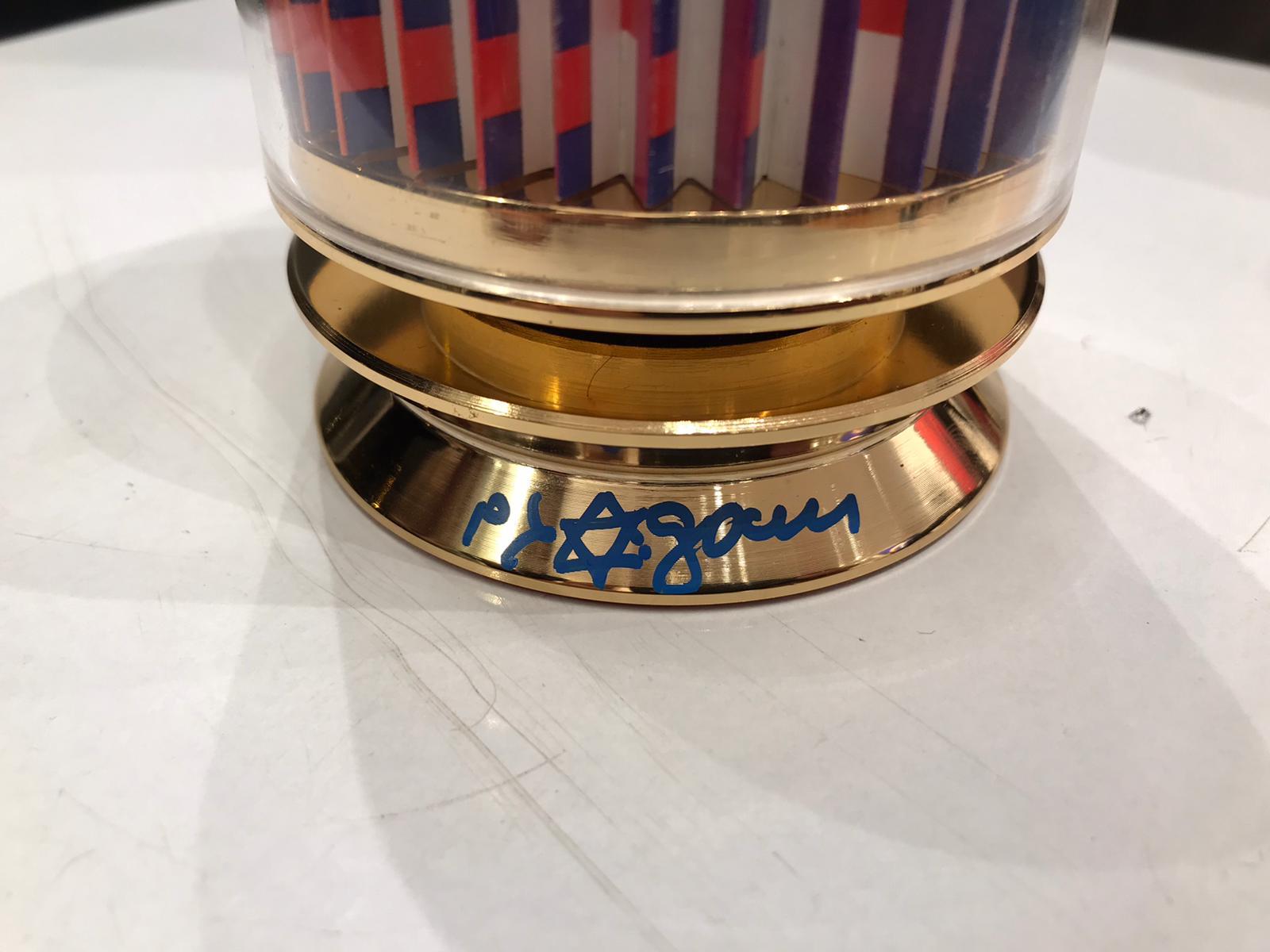 925 sterling silver kiddush cup with 24k gold plated which fits inside the revolving Agam serigraph contained in the lucite cylinder. Spin the cup to see the star of David magically appear. Agam's own Hebrew typography is imprinted on top of the