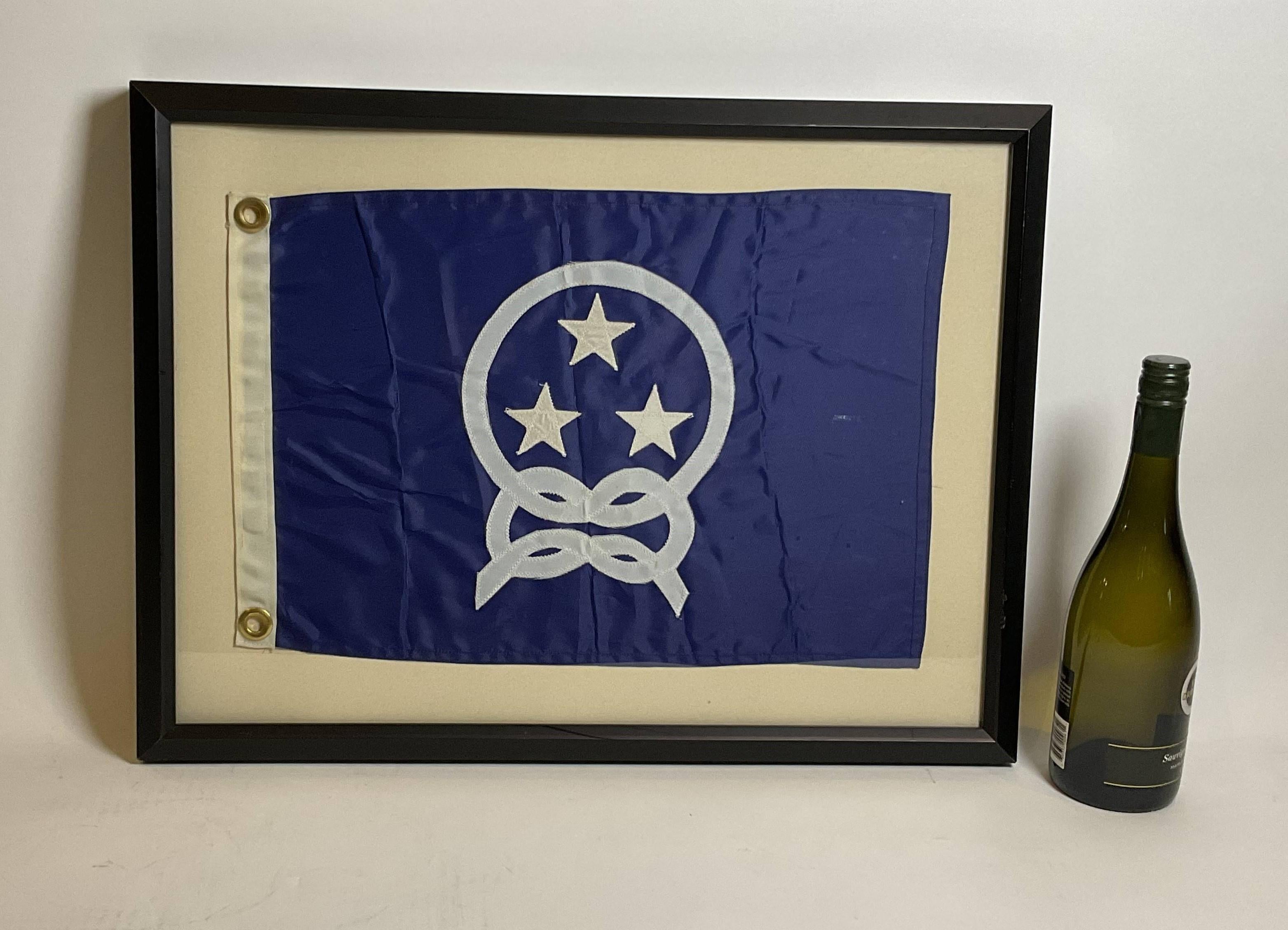 Nautical boat flag in frame. Yacht Club Commodores flag showing three stars surrounded by a knotted rope. White hoist with brass grommets. Set into a custom frame.

Weight: 5 lbs
Overall Dimensions: 18