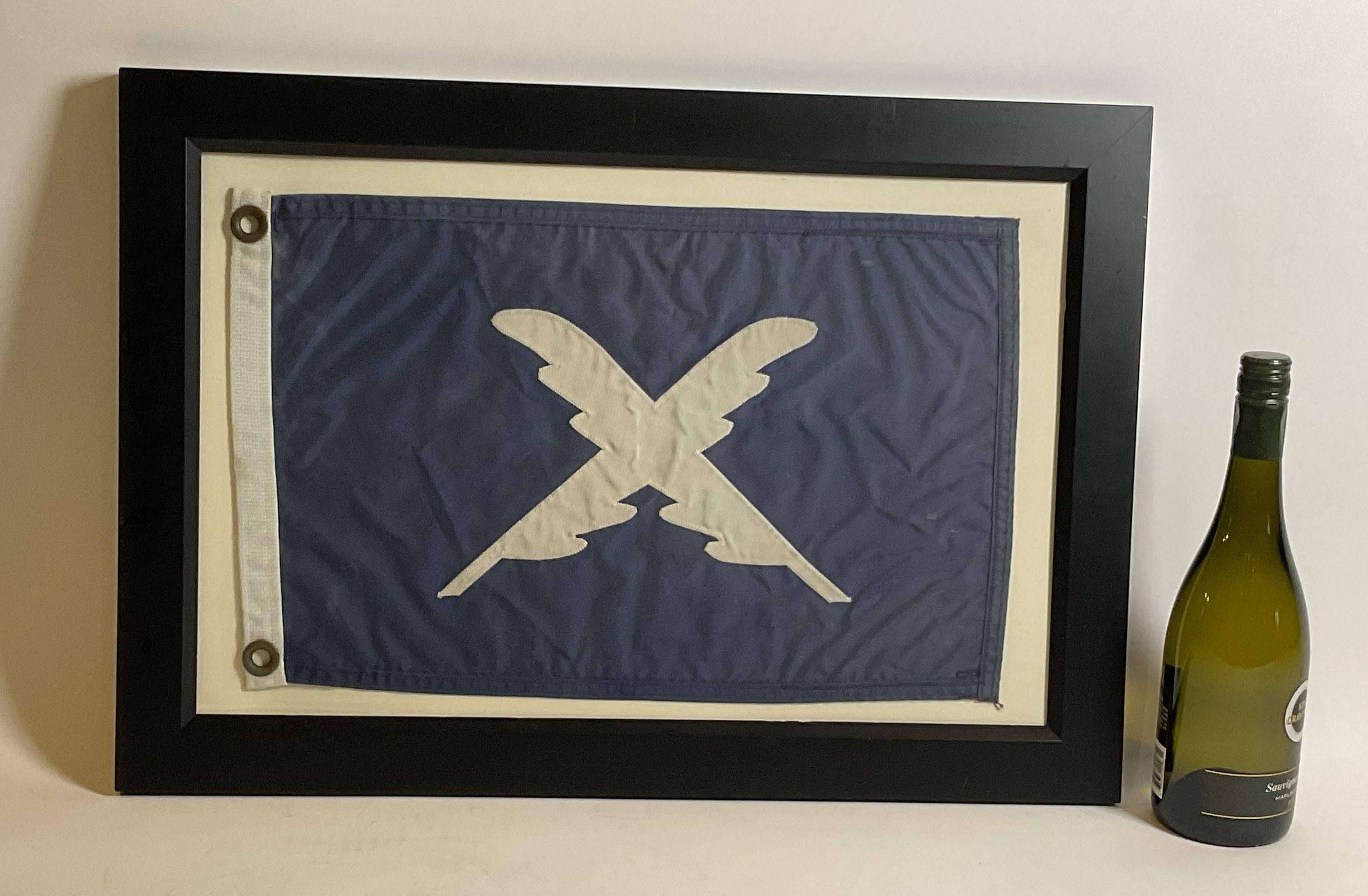 Nautical flag in frame with glass. Blue flag with crossed feathered quills. Blue field with white applied letters. White hoist with brass grommets.

Weight: 5 lbs.
Overall Dimensions: 17