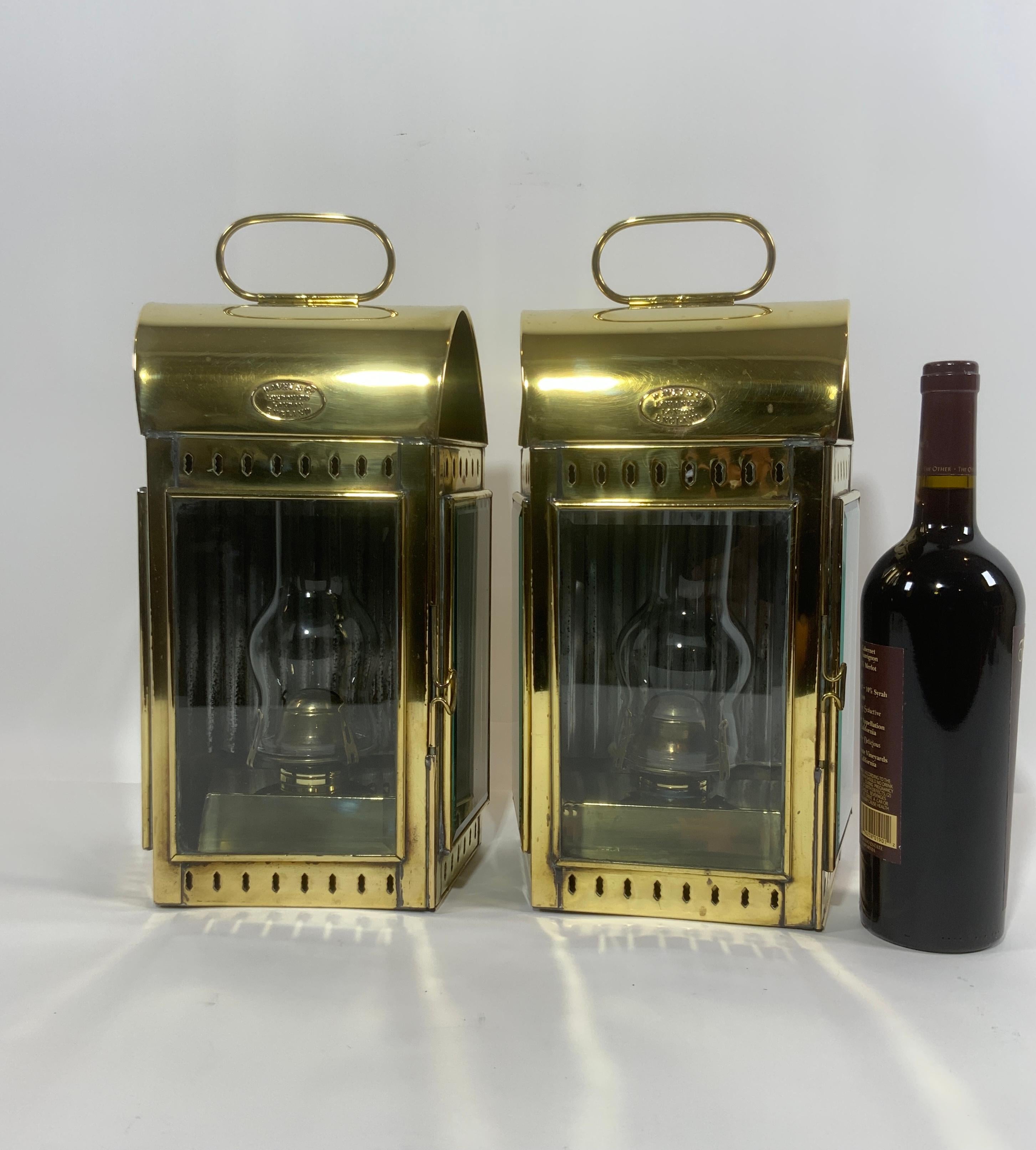 Pair of brass yacht cabin lanterns by venerable English maker Davey of London. Fine pair of matching oil lanterns with burner and globes, reflector panels are attached in both and they are fitted with hinged doors. Embossed brass makers badges from