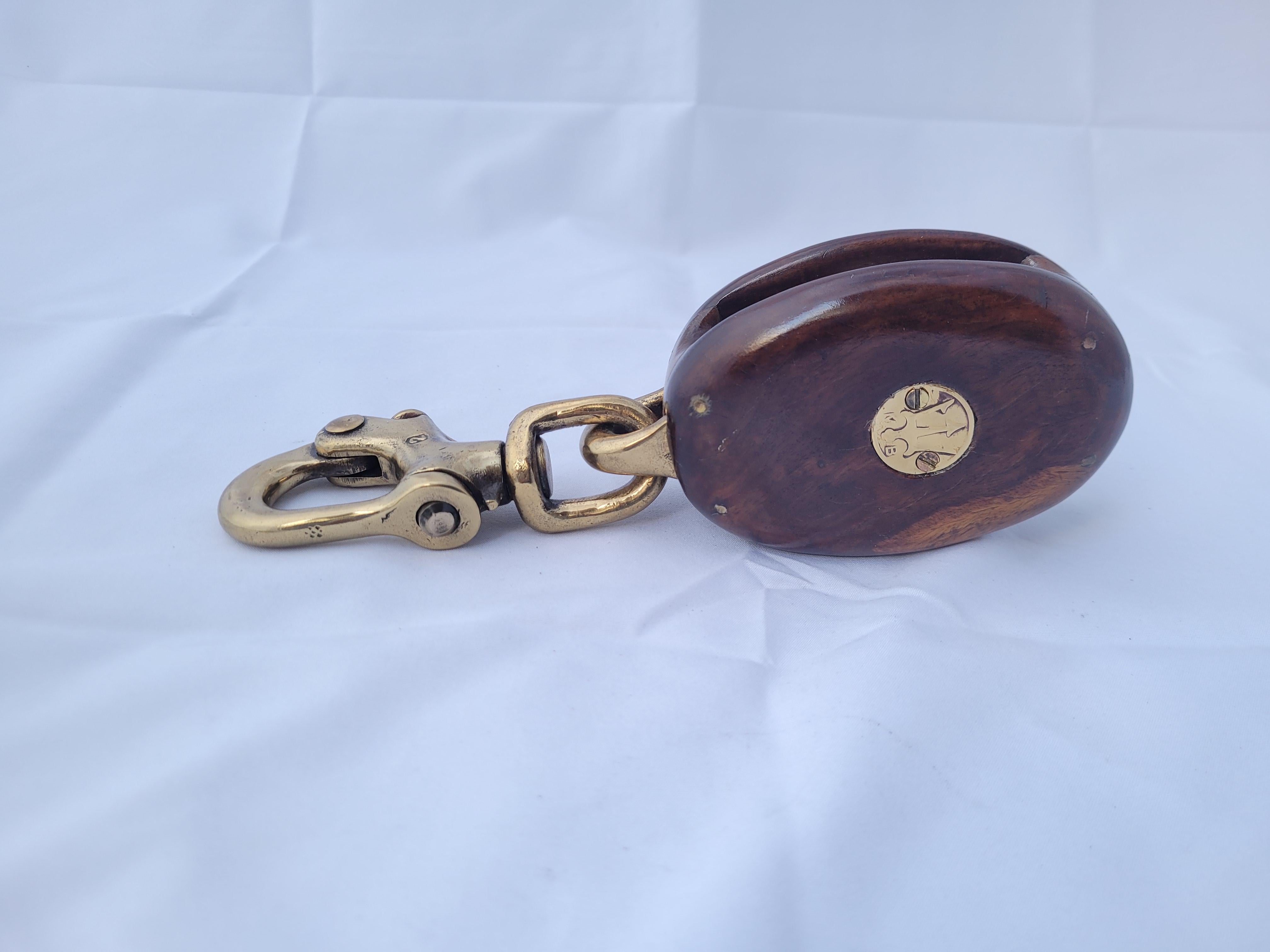 Choice marine block by Merriman of Boston. Rosewood with highly polished brass pulley, pins, shackle, and badges with trident forks. Amazing finish. Great nautical accent. First Class.

Weight 2 lbs.
Overall Dimensions 2