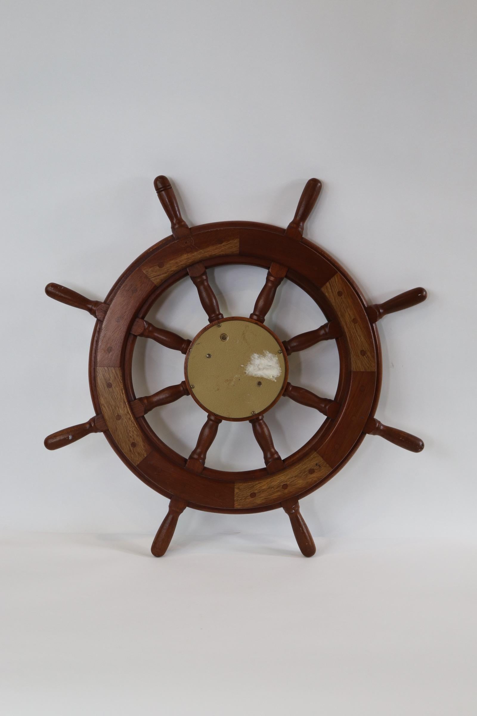 Eight spoke mahogany ships wheel with extensive Hollywood inlay and striking ships clock in brass case. Weight is 12 pounds.
