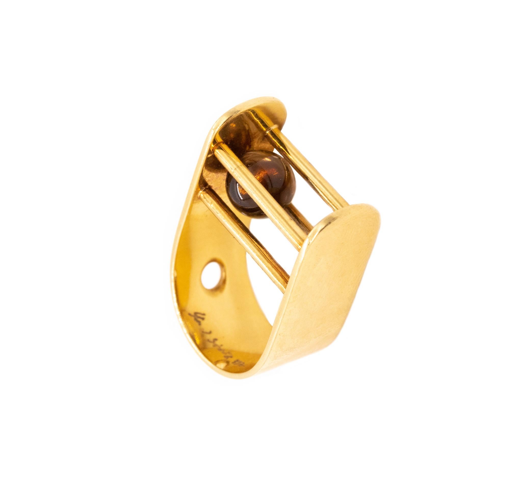 A kinetic ring designed by Yael Sonia.

This sculptural art-piece is crafted in 18k solid yellow gold, with a high polished finish. The design is composed by an U-shaped element with four pins that hold a sphere carved from natural translucent