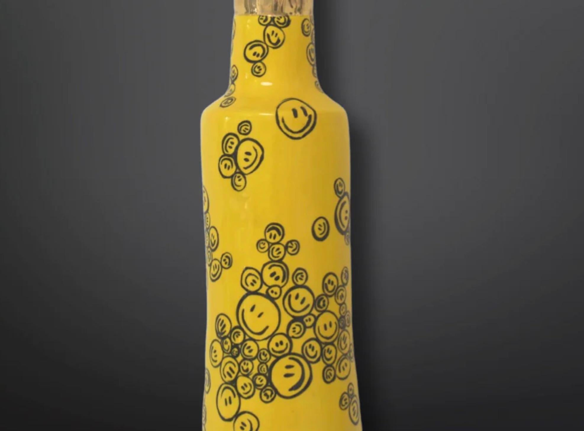 Bubbling Smiles Bullet Sculpture, una pieza única de arte en cerámica hecha a mano que seguro que añade un toque único y alegre a cualquier hogar u oficina. Esta hermosa escultura en forma de bala presenta un fondo amarillo intenso con caritas