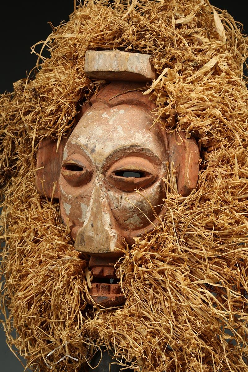 Yaka young men's initiation mask of carved wood with raffia collar, Congo (Democratic Republic of Congo), early 20th century. A hand-held mask used by boys coming out of the initiation camp and returning into the village. A flat mask held by the