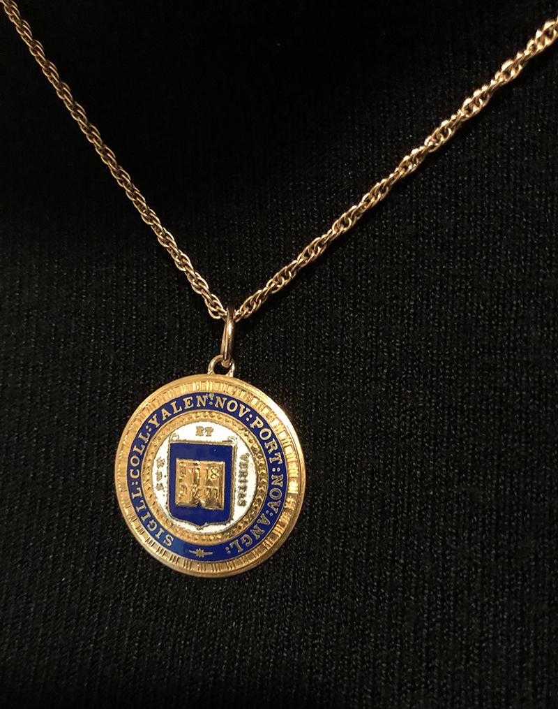 Yale University charm.  14K yellow gold.  In the center is an open book, with Hebrew lettering, surrounded by a white enamel border with applied letters 'LUX ET VERITAS, Latin for LIGHT AND TRUTH.  An outer Yale blue enamel border says