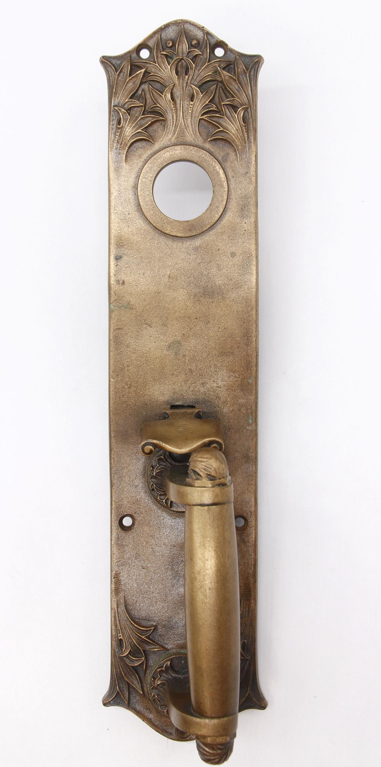 This is an antique 14.8 inch bronze door pull with a cylinder lock insert and thumb latch.  It was made by Yale & Towne in a Romanesque design called 