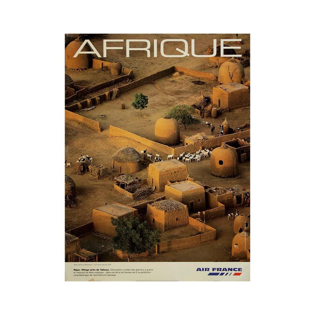 Cette affiche originale d'Air France datant de 2000, réalisée par le célèbre photographe aérien Yann Arthus-Bertrand, présente une vue époustouflante d'un village traditionnel Haoussa près de Tahoua, au Niger. Publiée à une époque où la compagnie