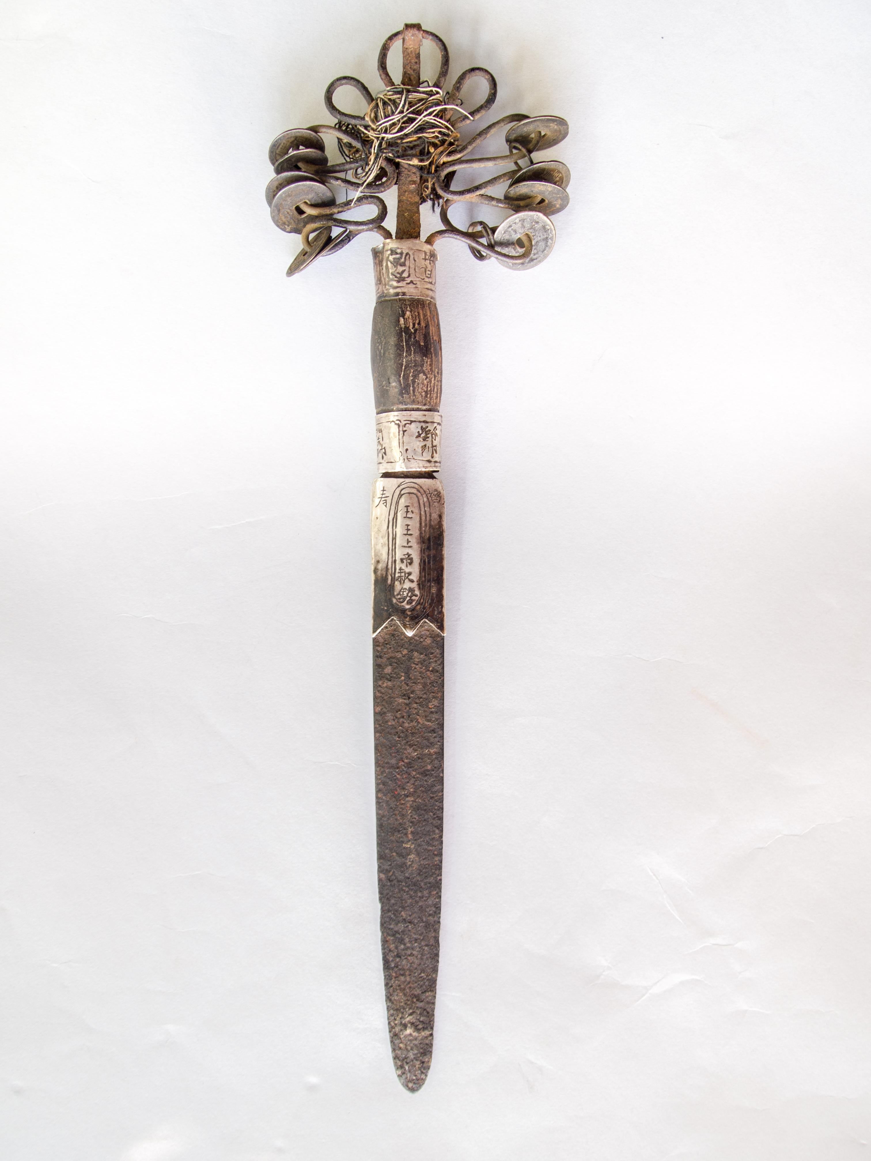 Yao Ritual Dagger or Dao. Iron with antique coins and silver banding inscribed with Chinese characters, Vietnam, early 20th century.
Used by a Yao priest or shaman in a ritual setting, a powerful aid when confronting the spirits on behalf of an
