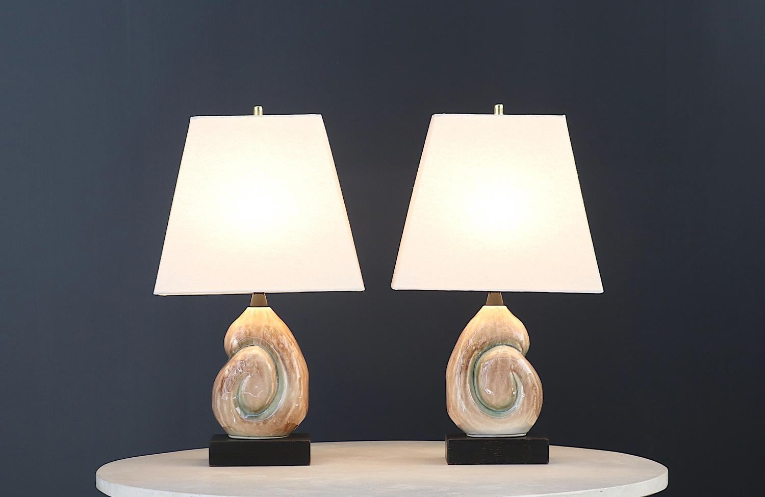 Illuminate your space with the allure of mid-century modern elegance with the Yasha Heifetz Ceramic Nautilus Shell Table Lamps, crafted in the 1950s. Designed and manufactured in the United States by Yasha Heifetz, these lamps feature glazed ceramic