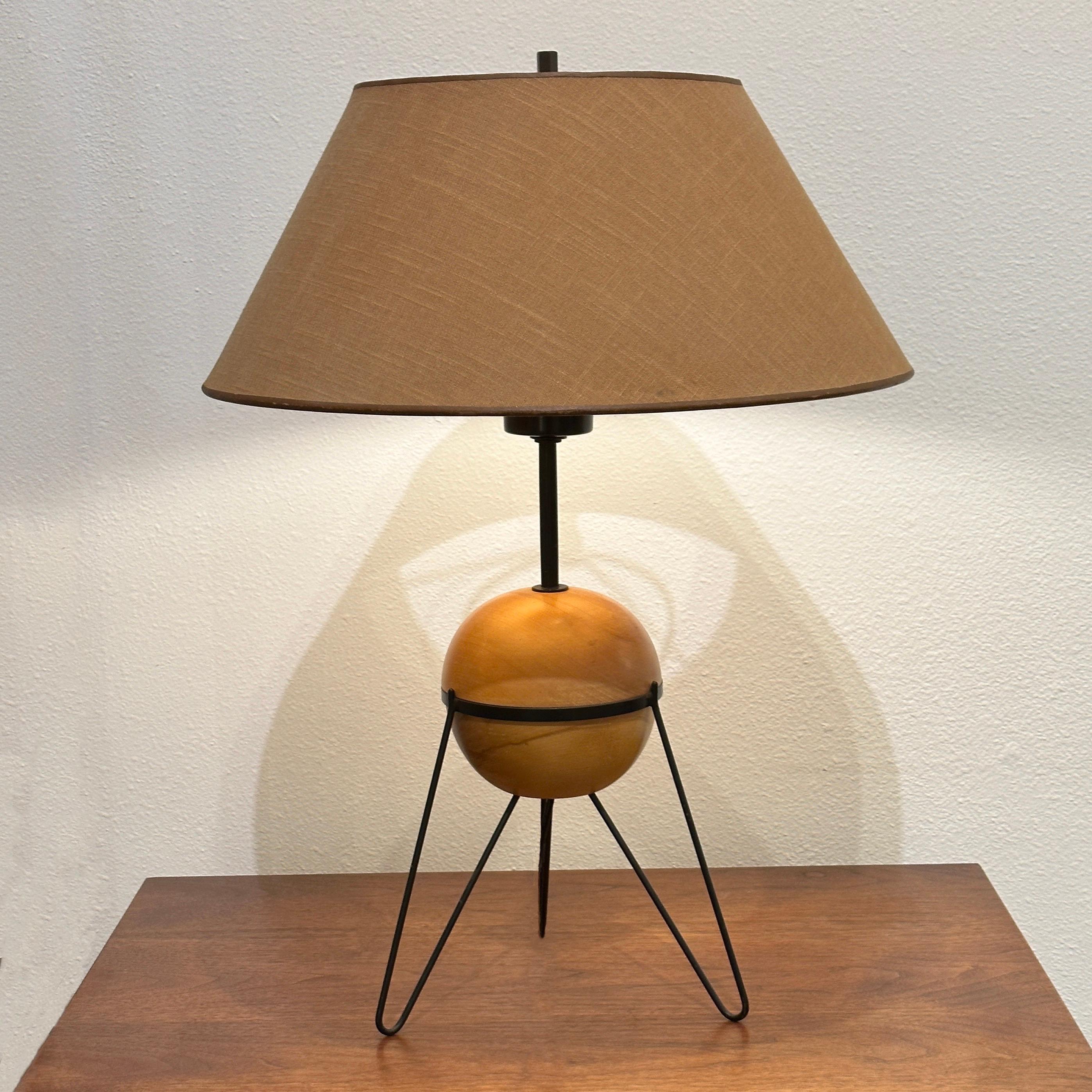 Rare table lamp designed by Yasha Heifetz for The Heifetz Company in the 1950s, consisting of a natural birch globe with painted metal tripod hairpin legs. This example features the original shade in a tan linen on styrene.

Measures 26